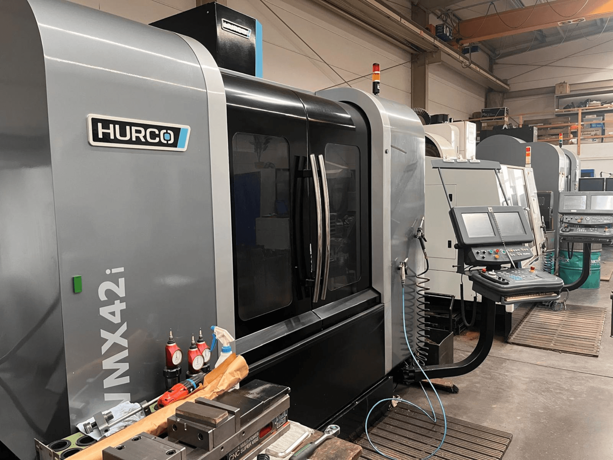 Macchina CNC Hurco VMX42i in un'officina, vista frontale, con pannello di controllo e vari utensili sul banco di lavoro.