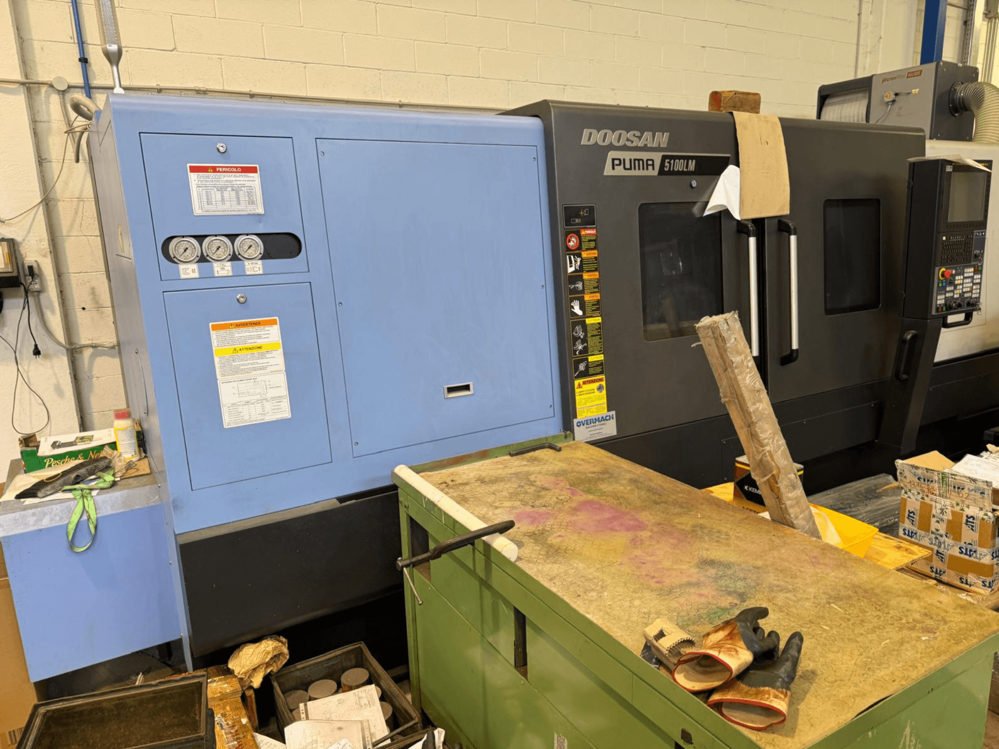 Macchina CNC Doosan Puma 5100LM e pannello di controllo, vista laterale. Indicatori ed etichette di avvertimento visibili sull'unità di controllo blu.