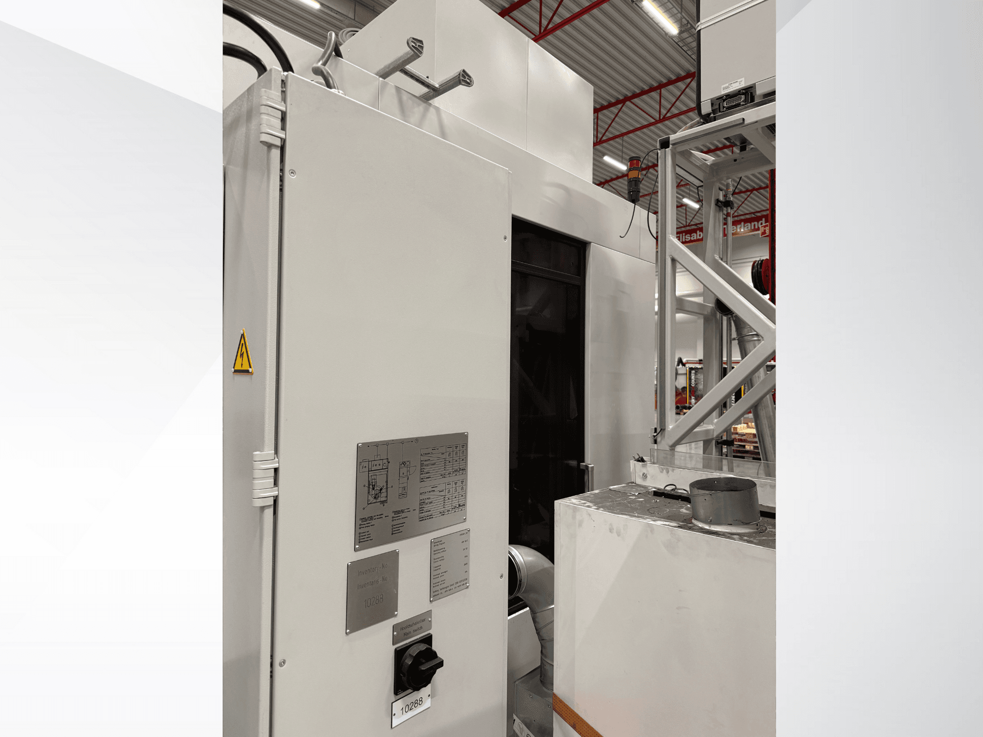 Vista laterale di una macchina industriale bianca con pannello di controllo ed etichetta di avvertimento, parte di un sistema automatizzato.