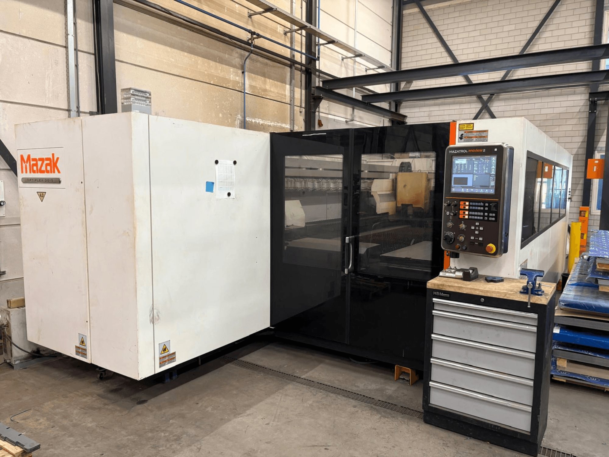 Macchina da taglio laser a CO₂ Mazak Optiplex 3015, vista frontale, con pannello di controllo e ambiente industriale.