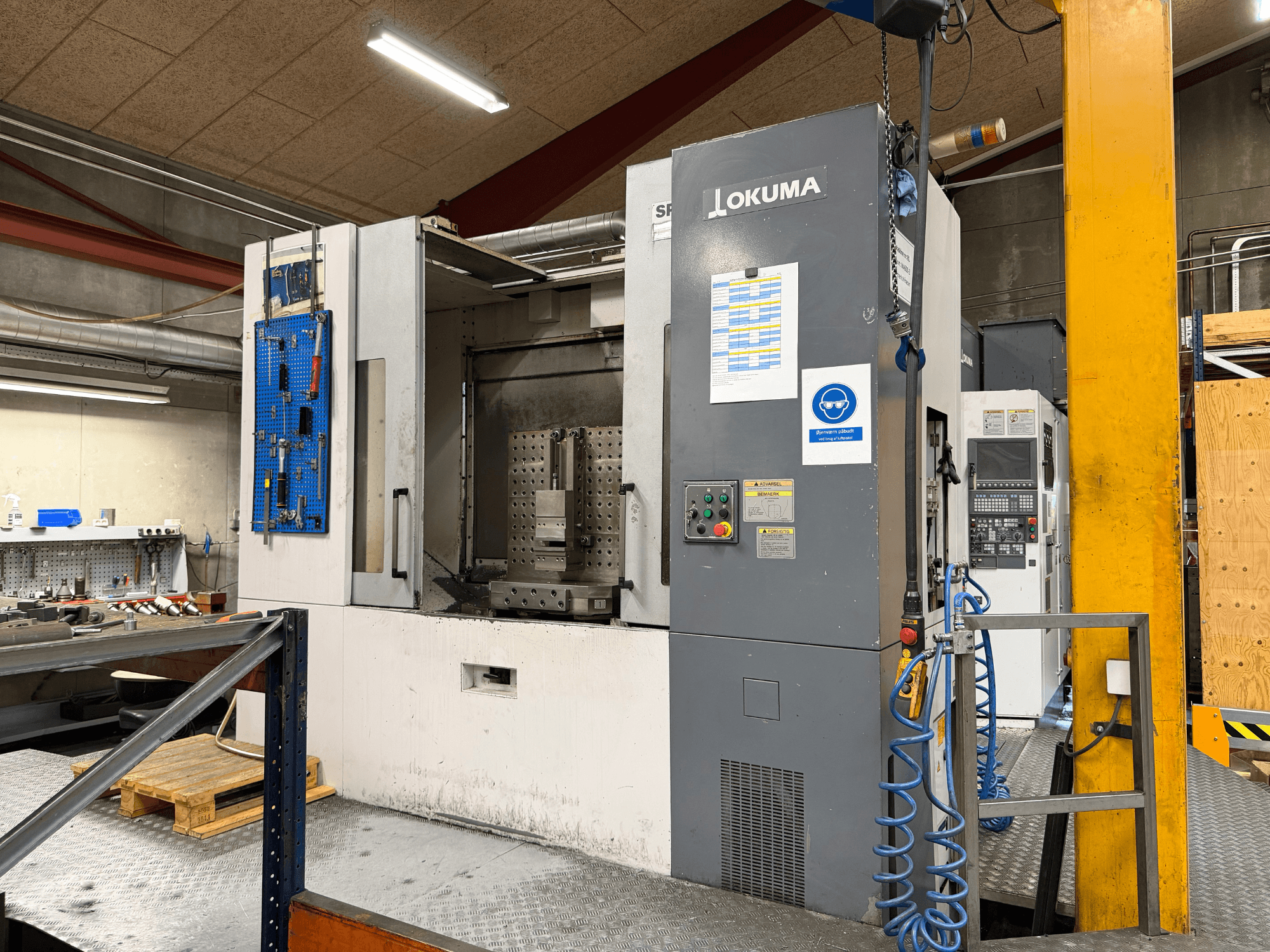 Centro di lavorazione orizzontale Okuma MA-600HB in un'officina, vista frontale che mostra il pannello di controllo e l'area di lavoro.