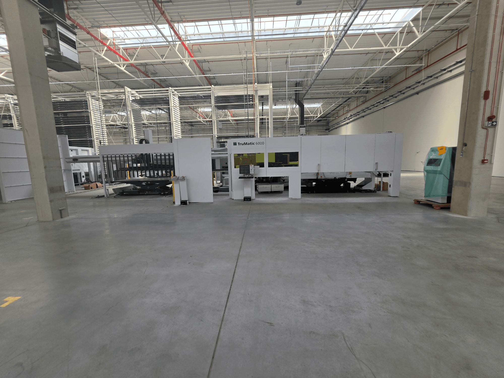 Macchina combinata punzonatrice-laser a fibra TRUMPF TruMatic 6000-1600 in un ampio magazzino, vista frontale.