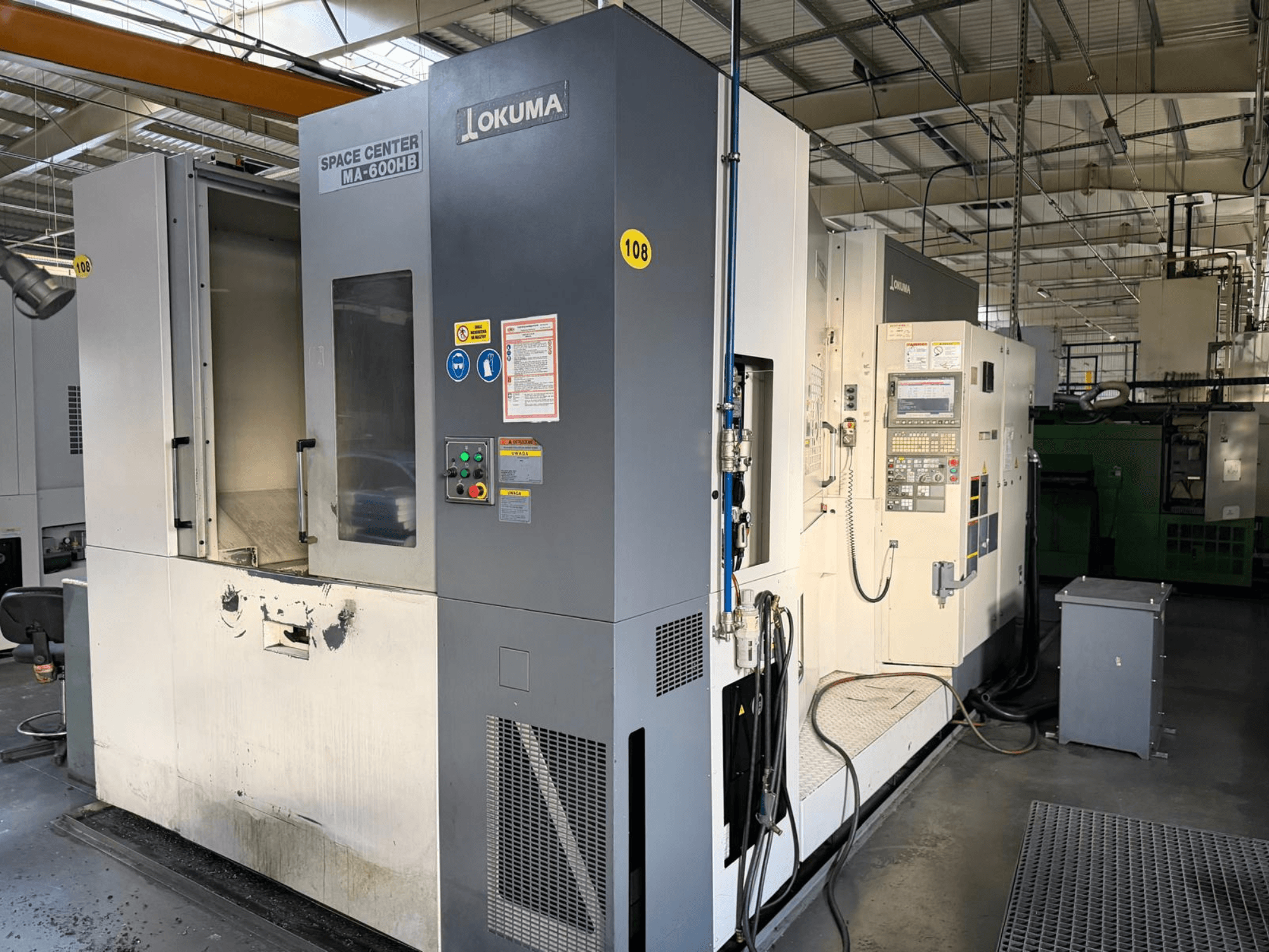 Centro di lavoro orizzontale Okuma MA-600 HB, vista frontale, con pannello di controllo e area di taglio con segni di usura visibili.