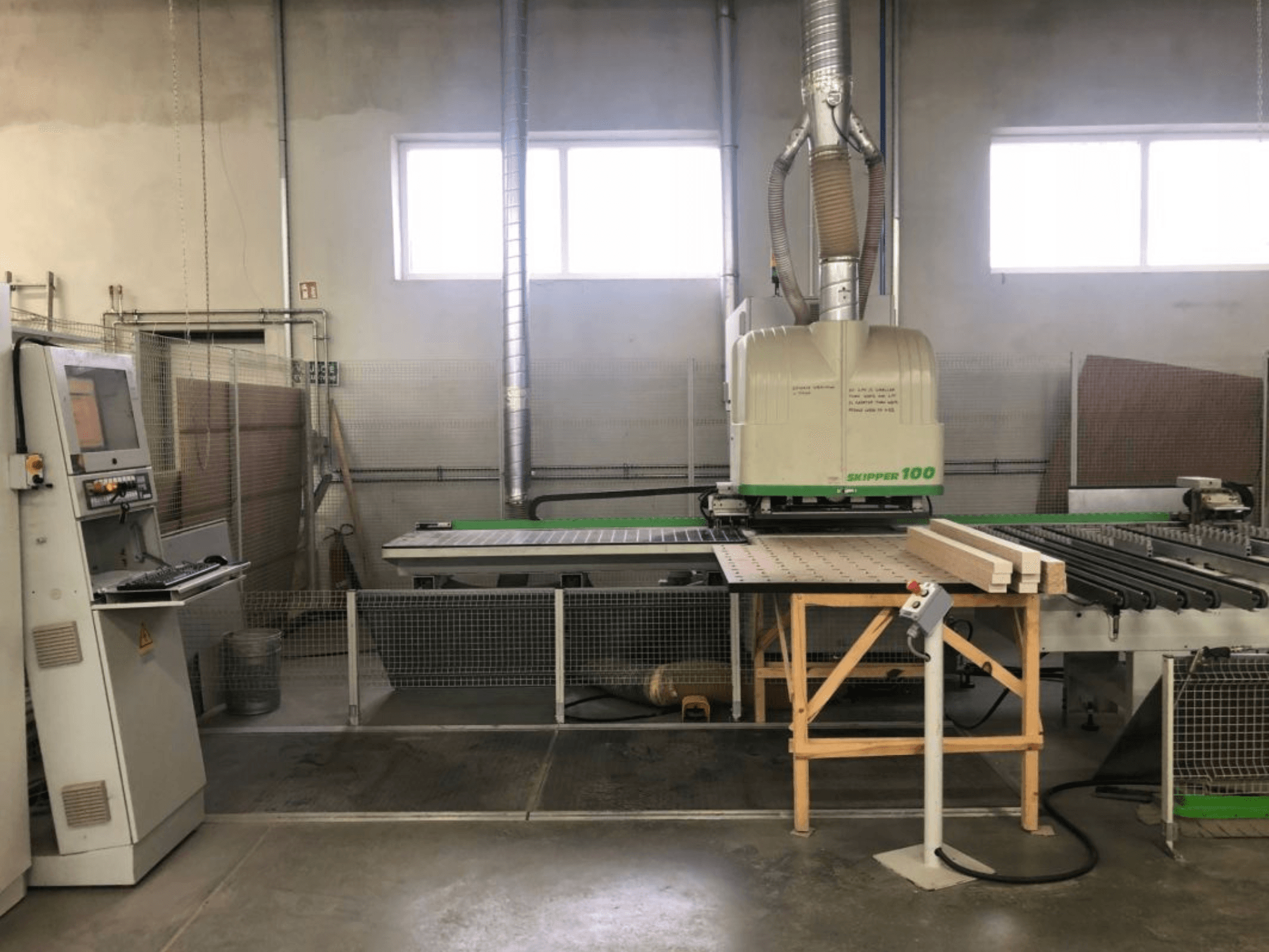 Centro di lavorazione CNC BIESSE SKIPPER 100 in un'officina; la vista frontale mostra la macchina con il pannello di controllo e il legno sul piano di lavoro.