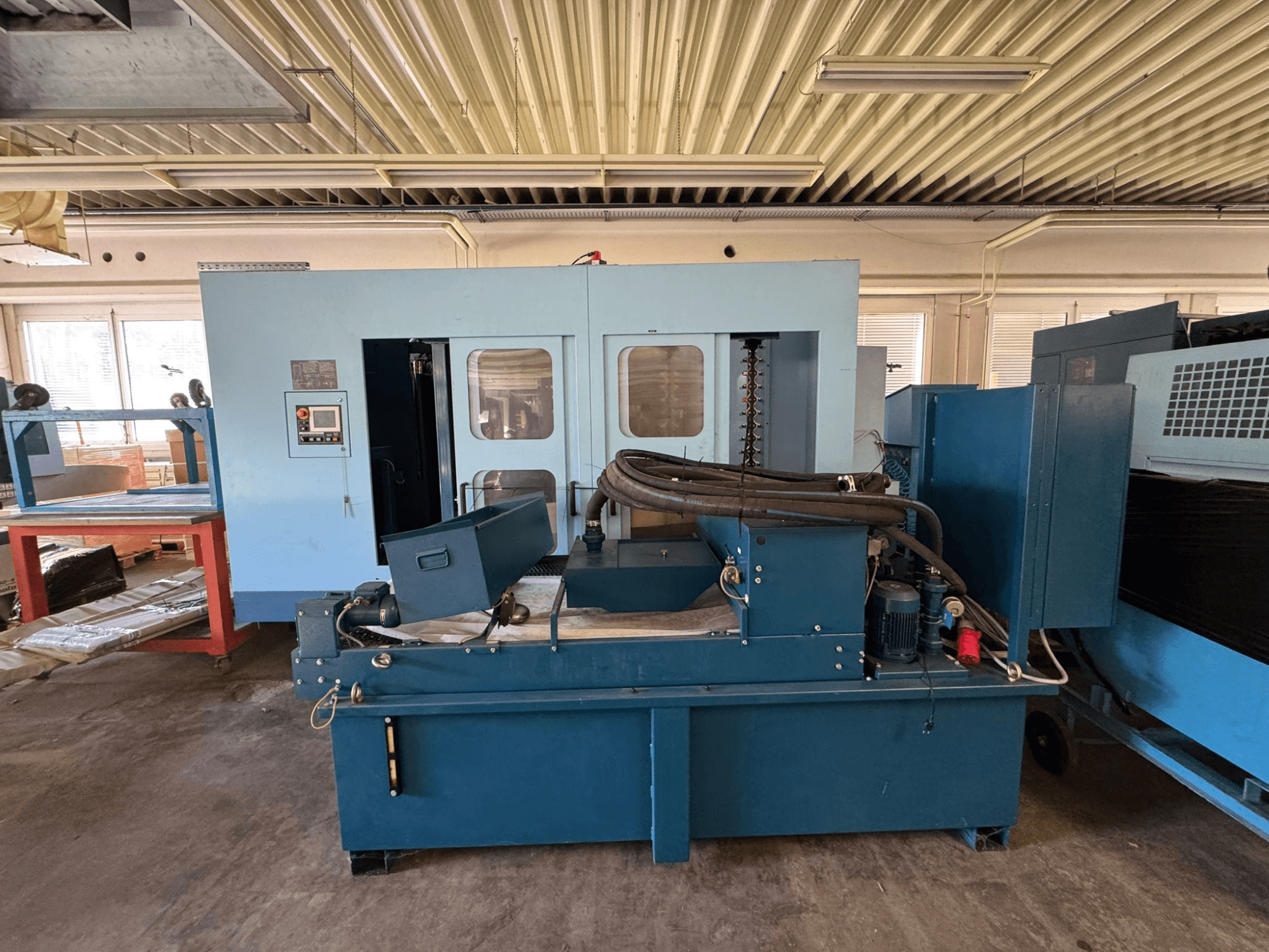 Centro di lavorazione orizzontale Matsuura H. Plus 405 di colore blu, vista frontale, con in primo piano il pannello di comando e i componenti della macchina.