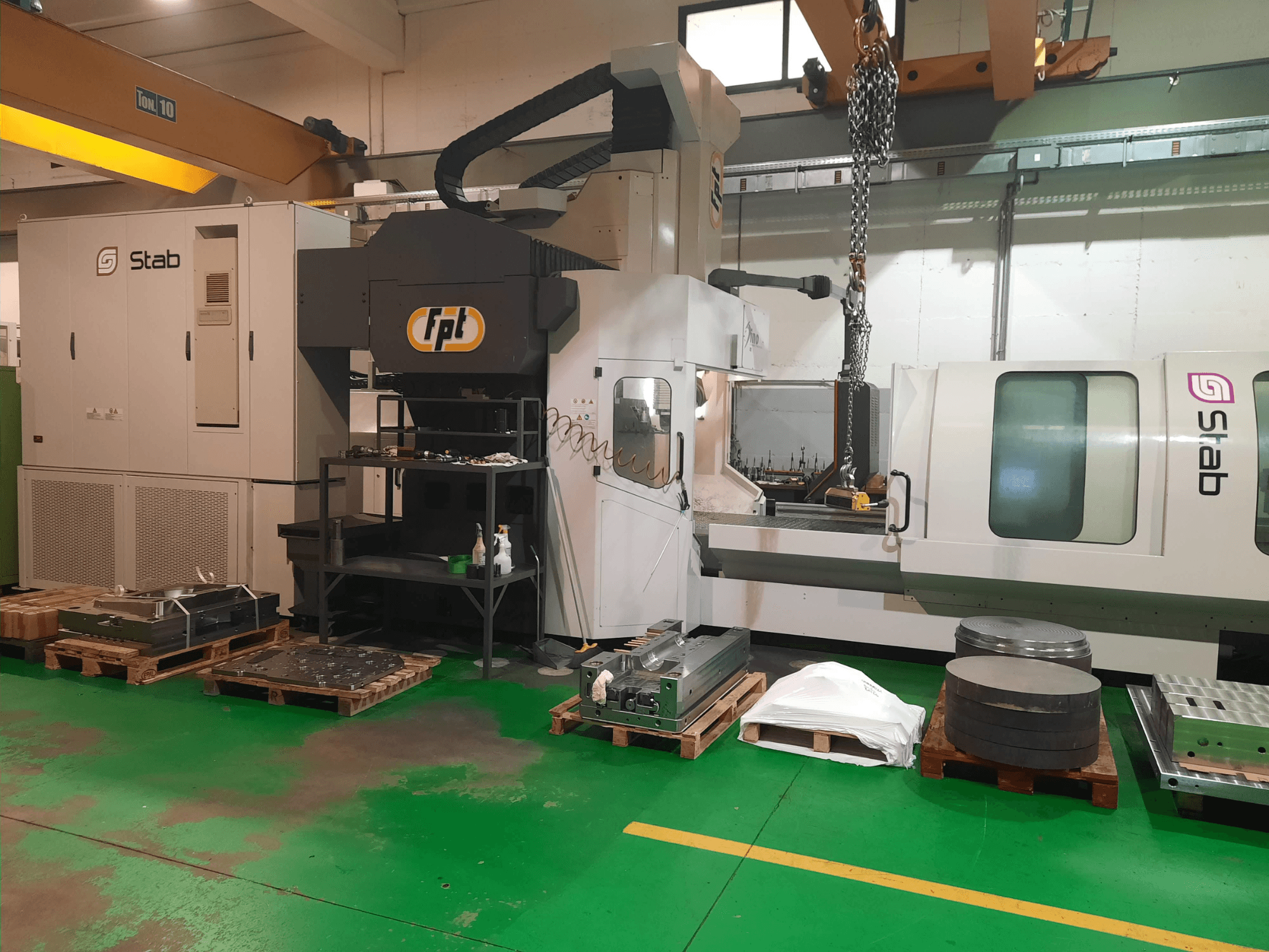 Fresatrice a banco FPT DINO in un'officina, vista frontalmente con utensili e materiali vicini su pallet.