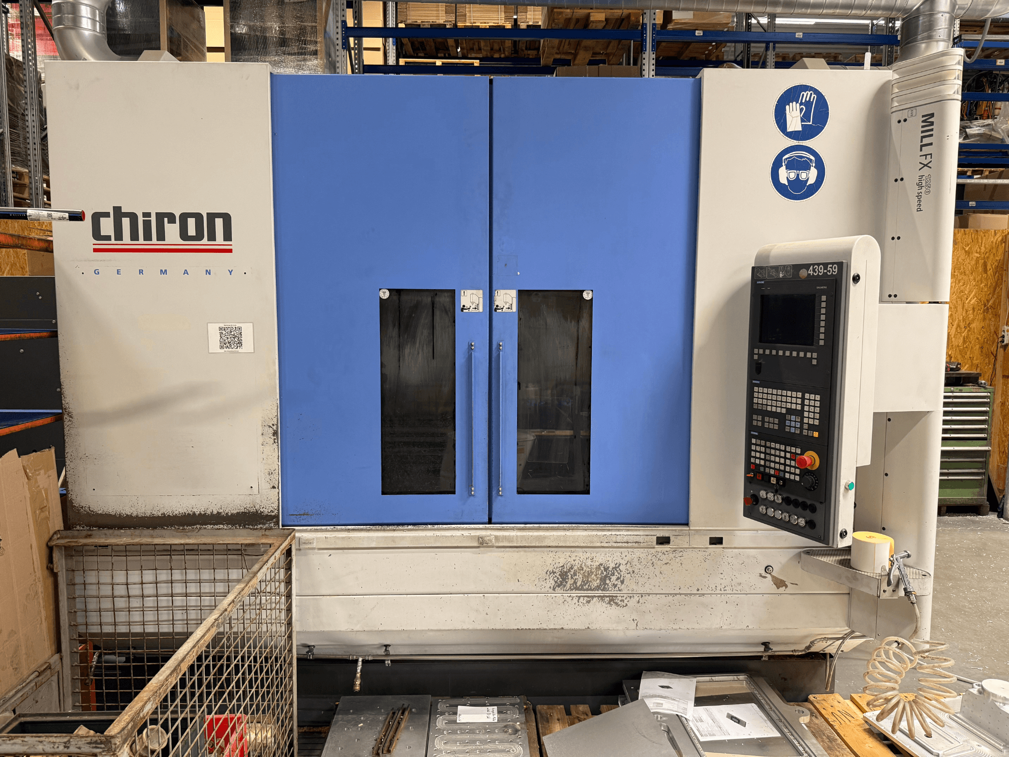 Centro di lavorazione verticale CHIRON MILL FX 1250, vista frontale, con pannello di controllo e simboli di sicurezza, pronto per lavori di precisione.