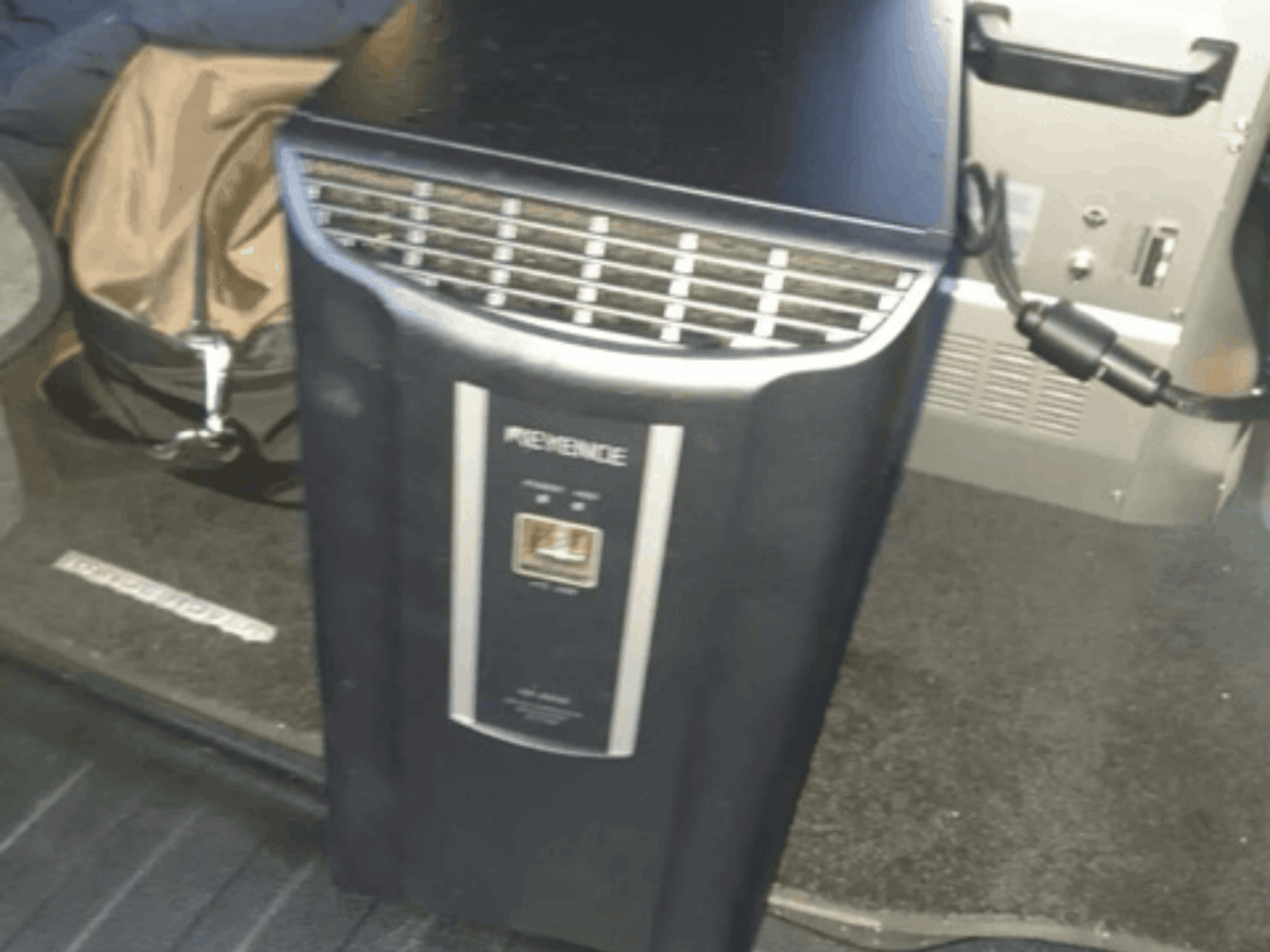 Il sistema di automazione KEYENCE IM-8030 in una vista frontale, che mostra il pannello di controllo e le bocchette, sullo sfondo dell'interno del veicolo.