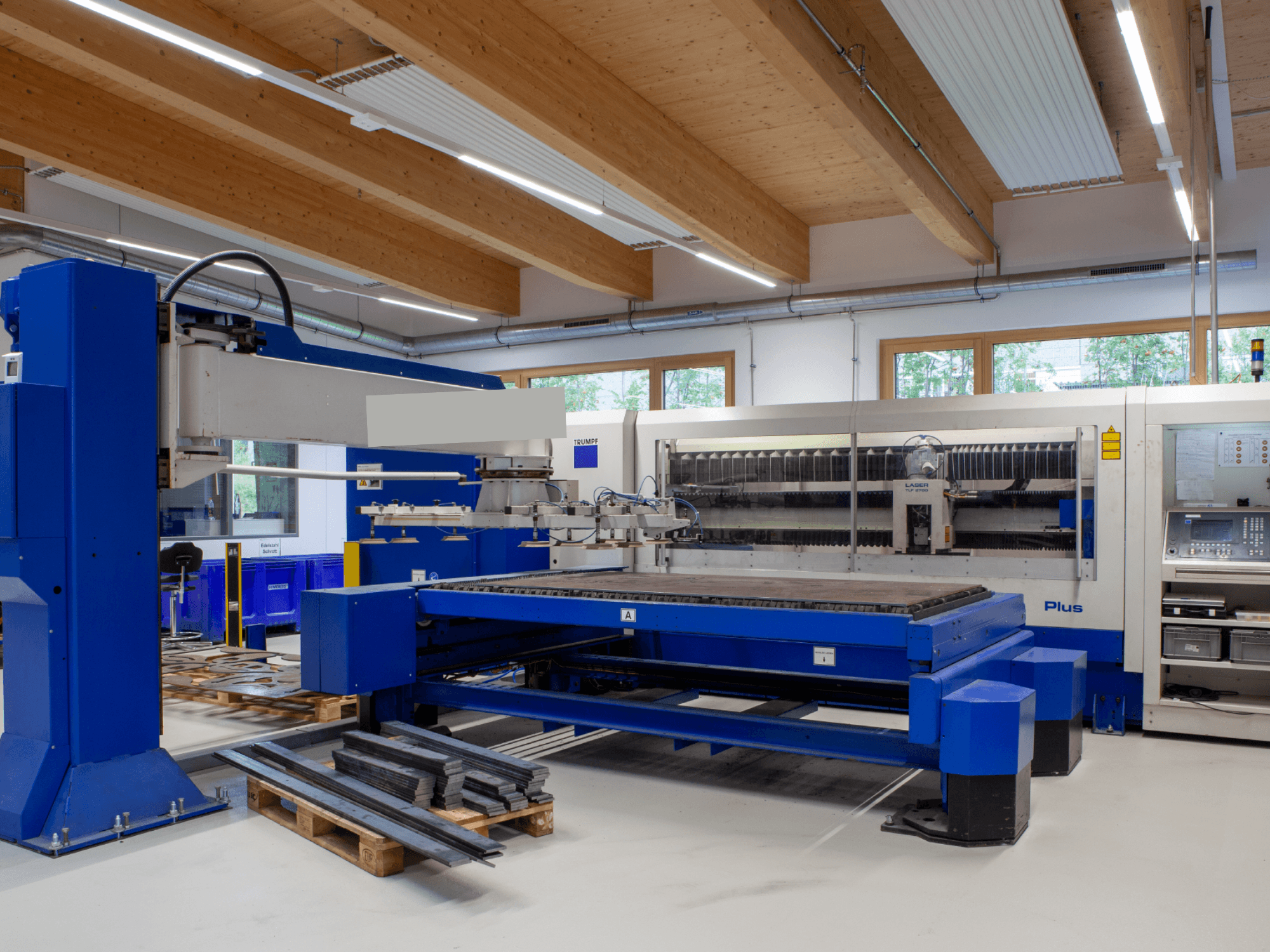 Macchina per il taglio laser a CO₂ TRUMPF TRUMATIC L 2530 Plus in un'officina, caratterizzata da un ampio piano di taglio e da un design industriale.