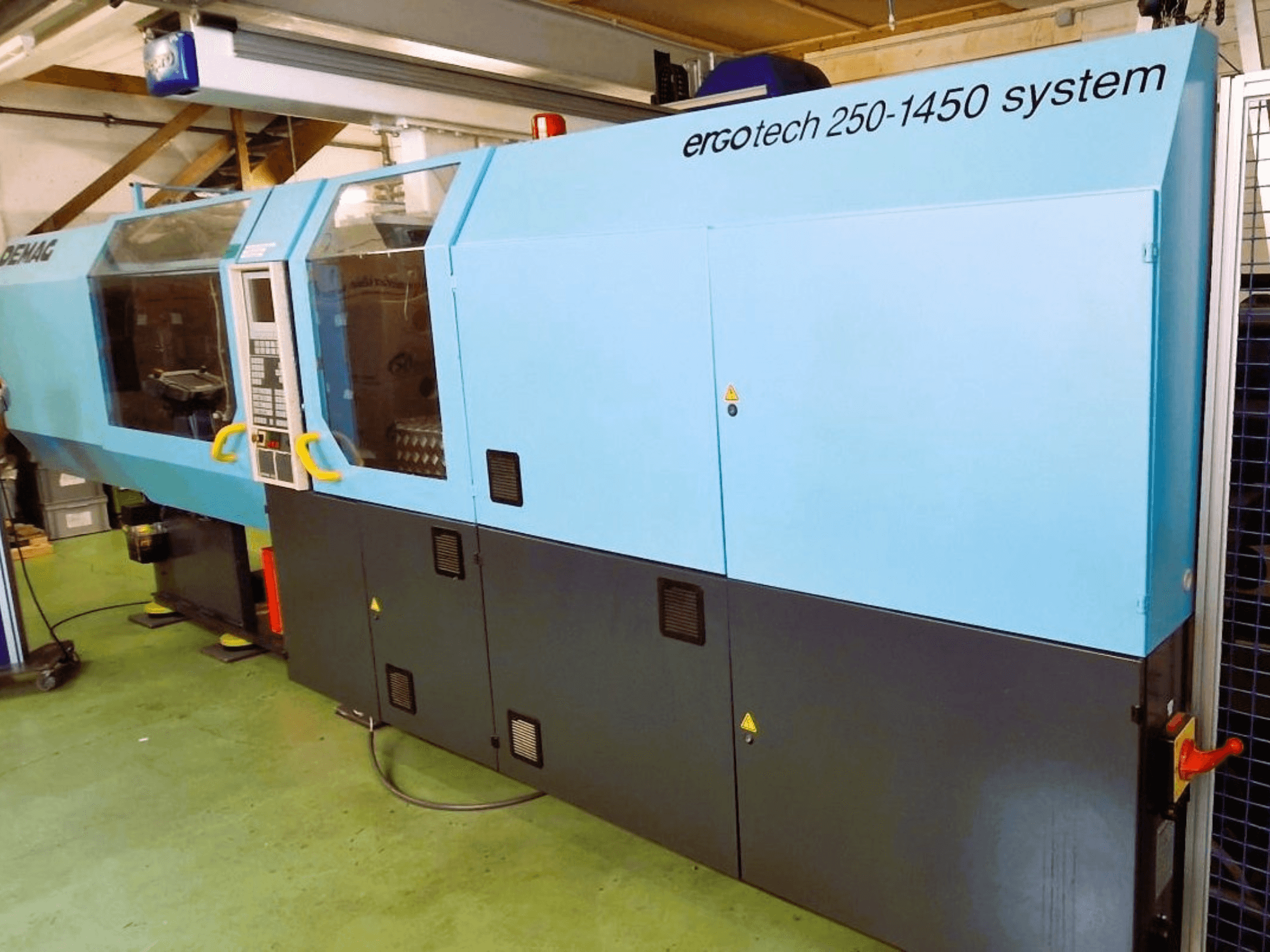 Macchina ad iniezione Ergotech 250-1450 system, vista frontale, colore blu e nero, con pannello di controllo e caratteristiche di sicurezza visibili.