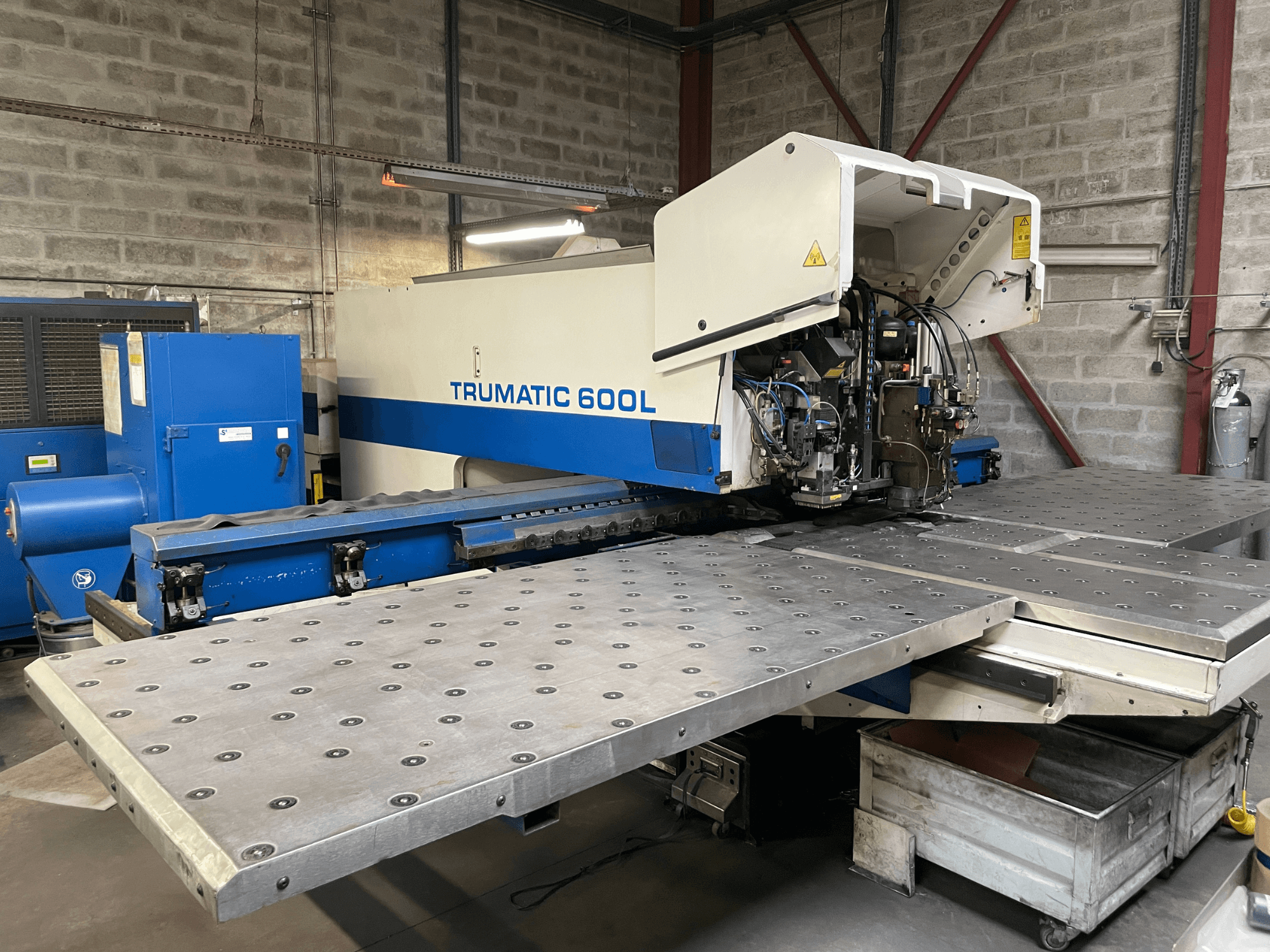 Macchina per il taglio laser CO2 TRUMPF TRUMATIC TC 600L, vista frontale con tavolo da taglio in metallo e pannello di controllo visibile.