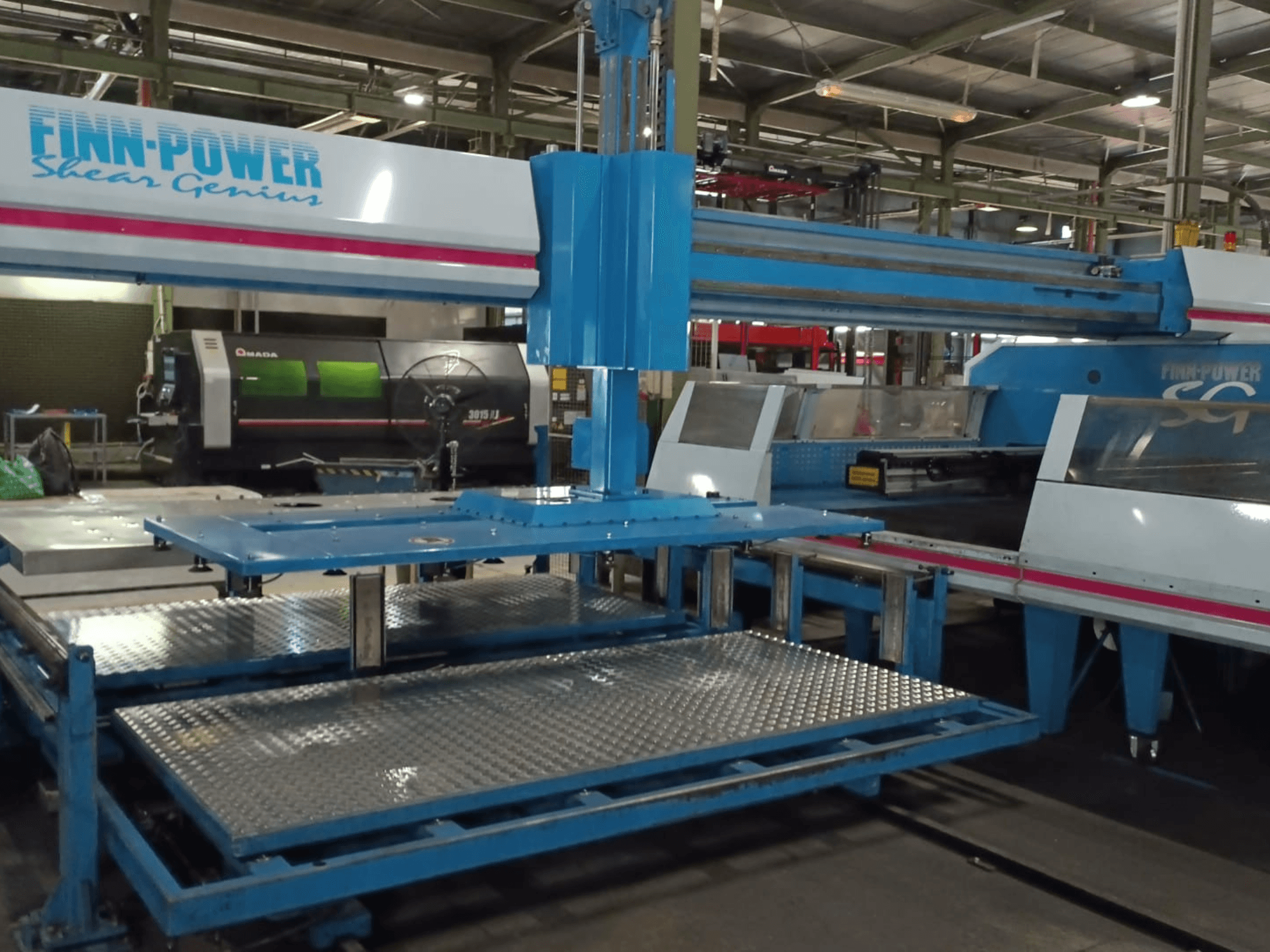 Punzonatrice CNC Finn-Power SG6 "Shear Genius" vista frontale, con tavoli in metallo e caratteristiche strutturali in evidenza.