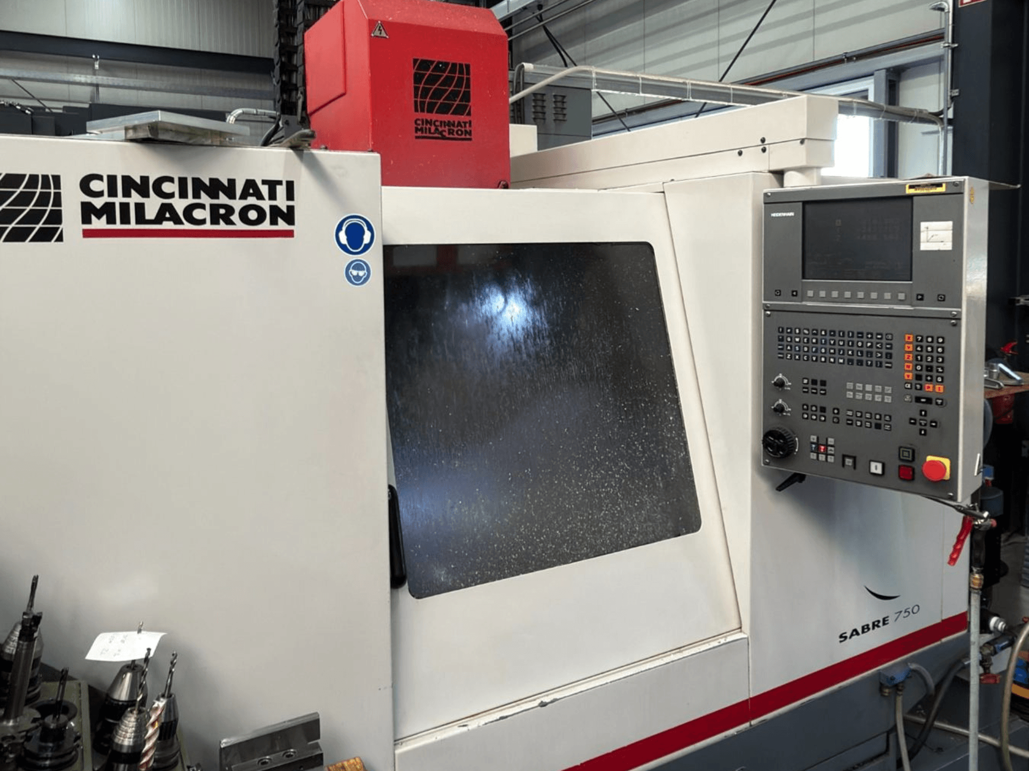 Centro di lavorazione verticale Cincinnati Milacron Sabre 750, vista frontale, con pannello di controllo e vetro parzialmente oscurato.