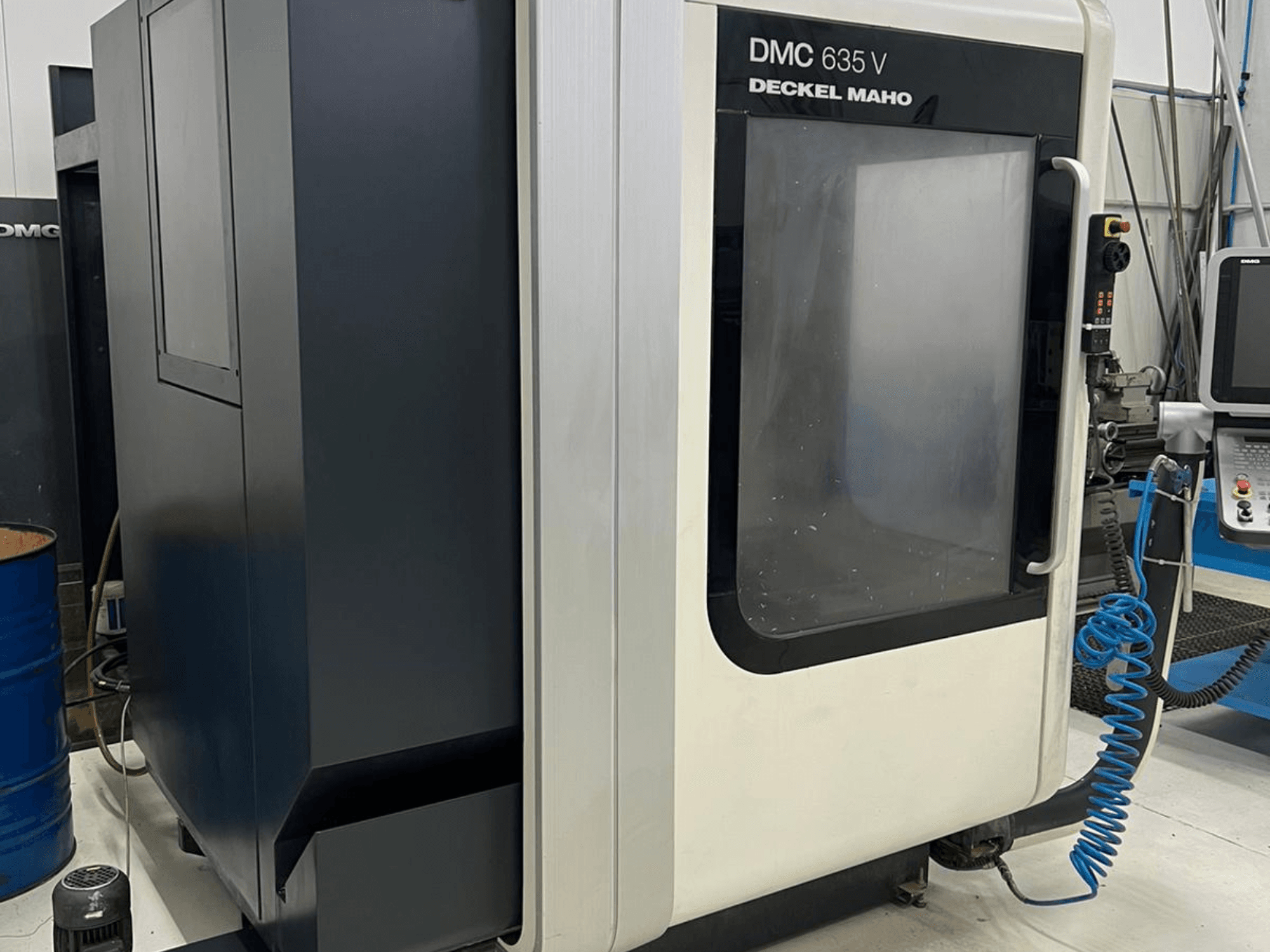 Fresatrice DMC 635 V di Deckel Maho, vista laterale che mostra il pannello di controllo e lo sportello di accesso parzialmente aperto.