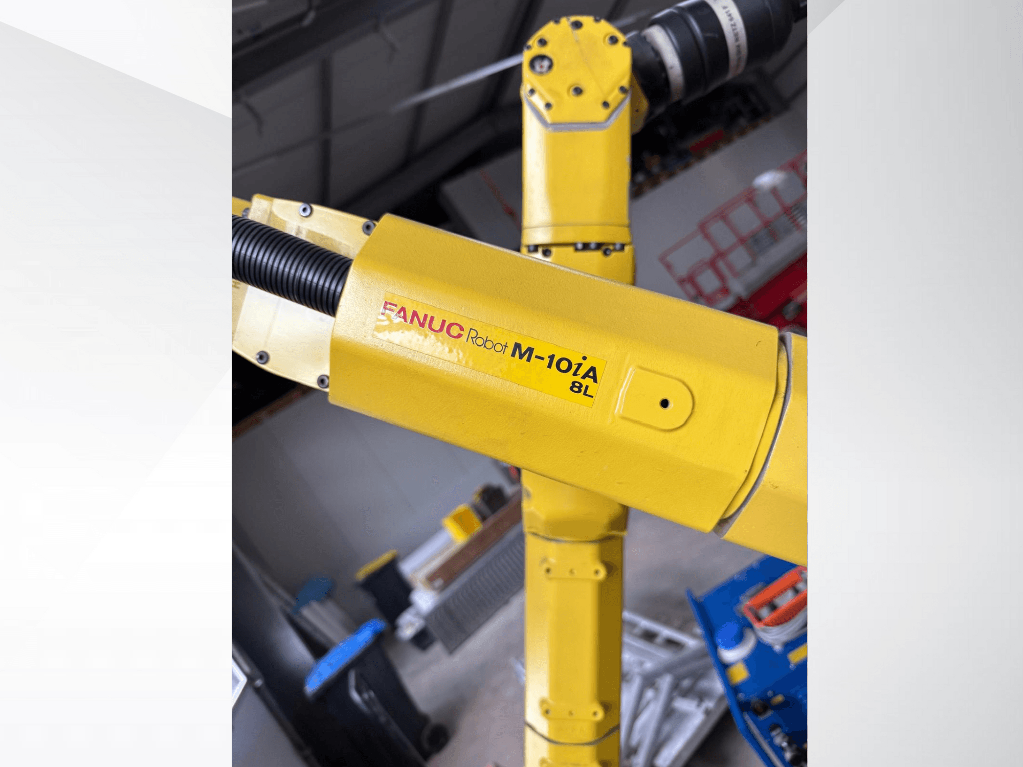 Robot FANUC M-10iA 8L in giallo, visto di lato, che mostra il giunto del braccio e i componenti meccanici in un ambiente industriale.