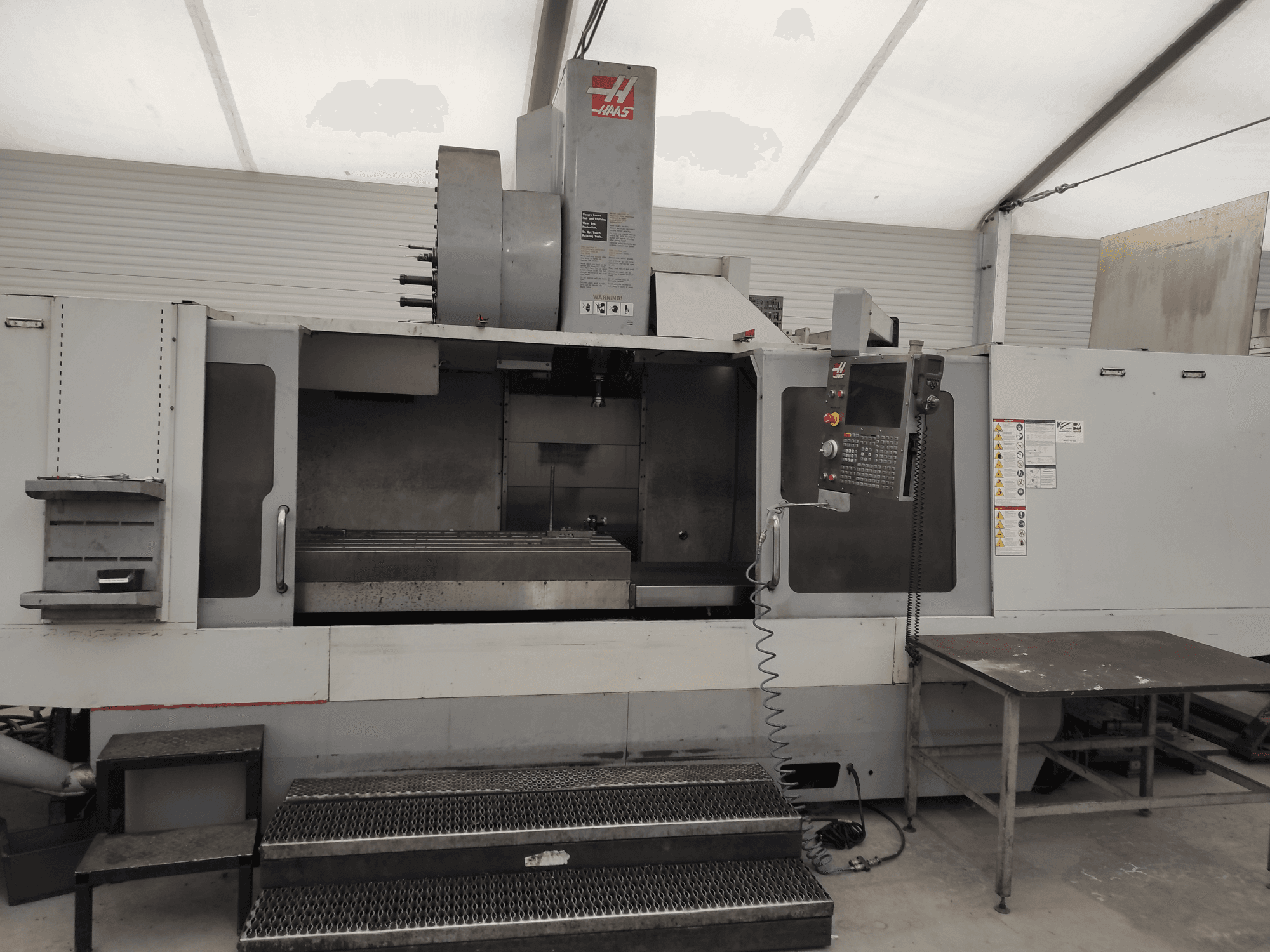 Centro di lavoro verticale HAAS VF-10/50HE, vista frontale che mostra il pannello di controllo, il basamento della macchina e il gradino accessibile per il funzionamento.