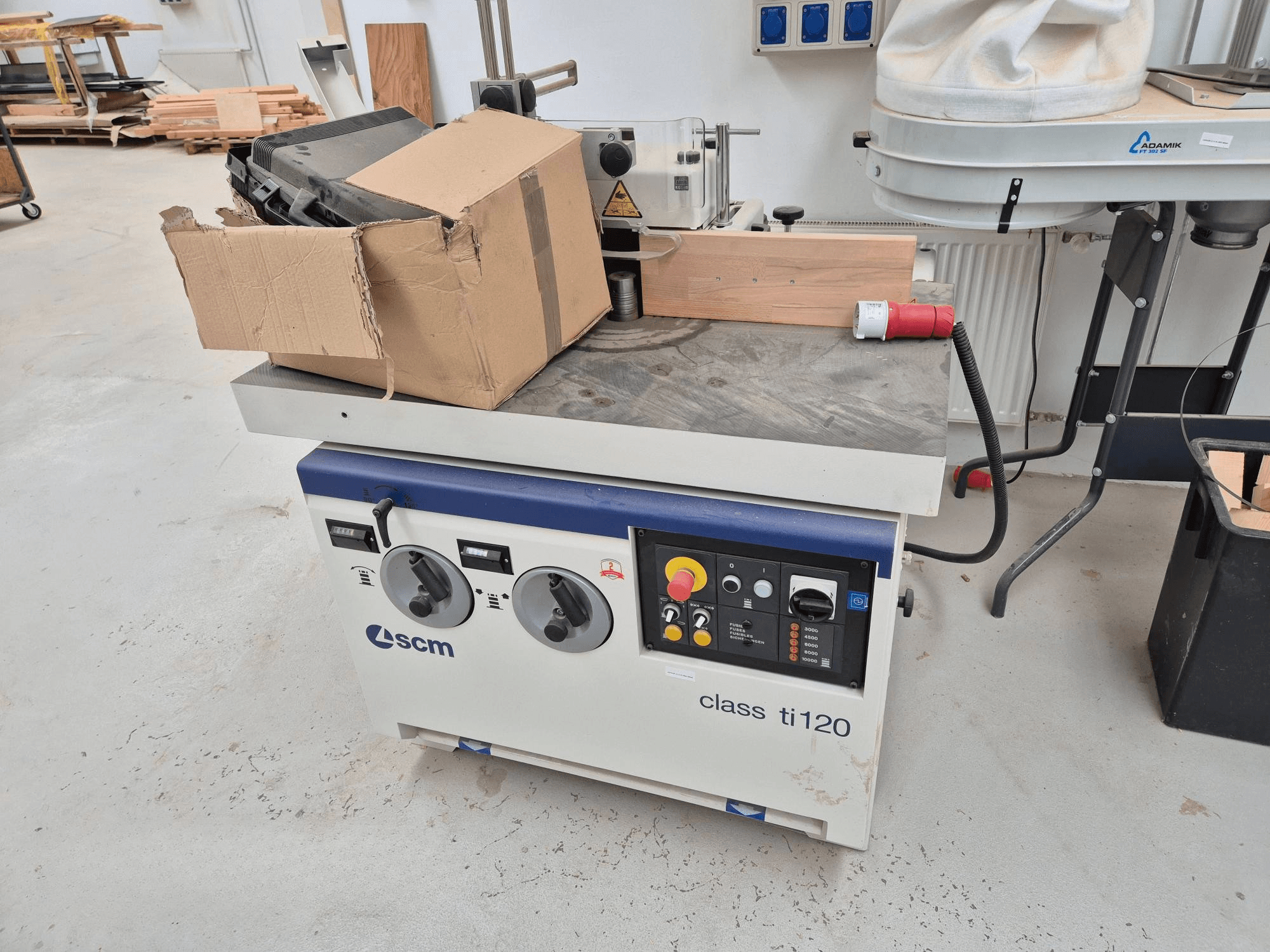 Macchina per la lavorazione del legno SCM classe ti120, vista frontale, presenta un pannello di controllo con manopole e pulsanti e una scatola di cartone allegata.