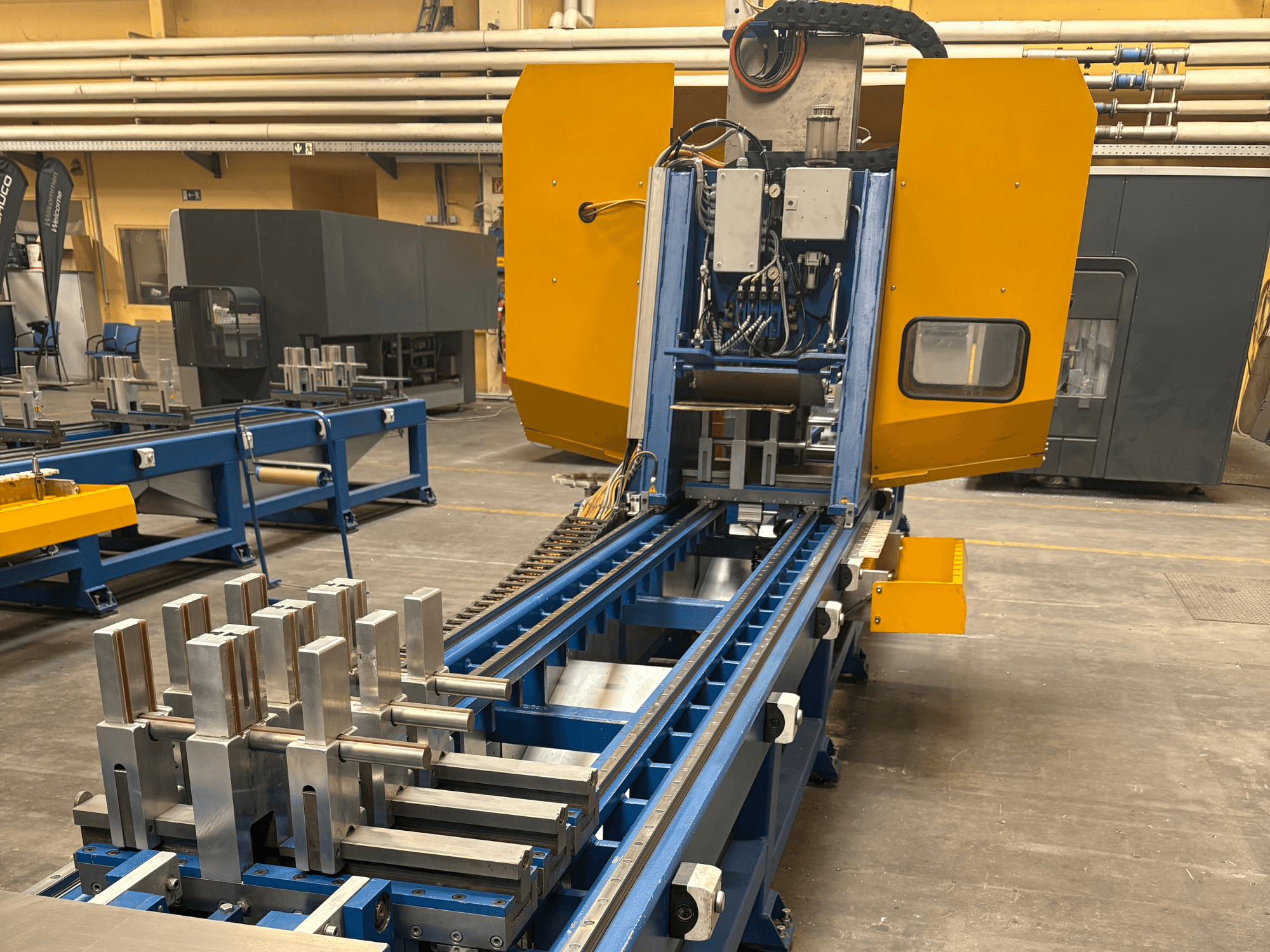 Vista frontale del Centro di lavoro universale PBX AL di SCHÜCO, che mostra pezzi metallici su un banco di lavoro blu.