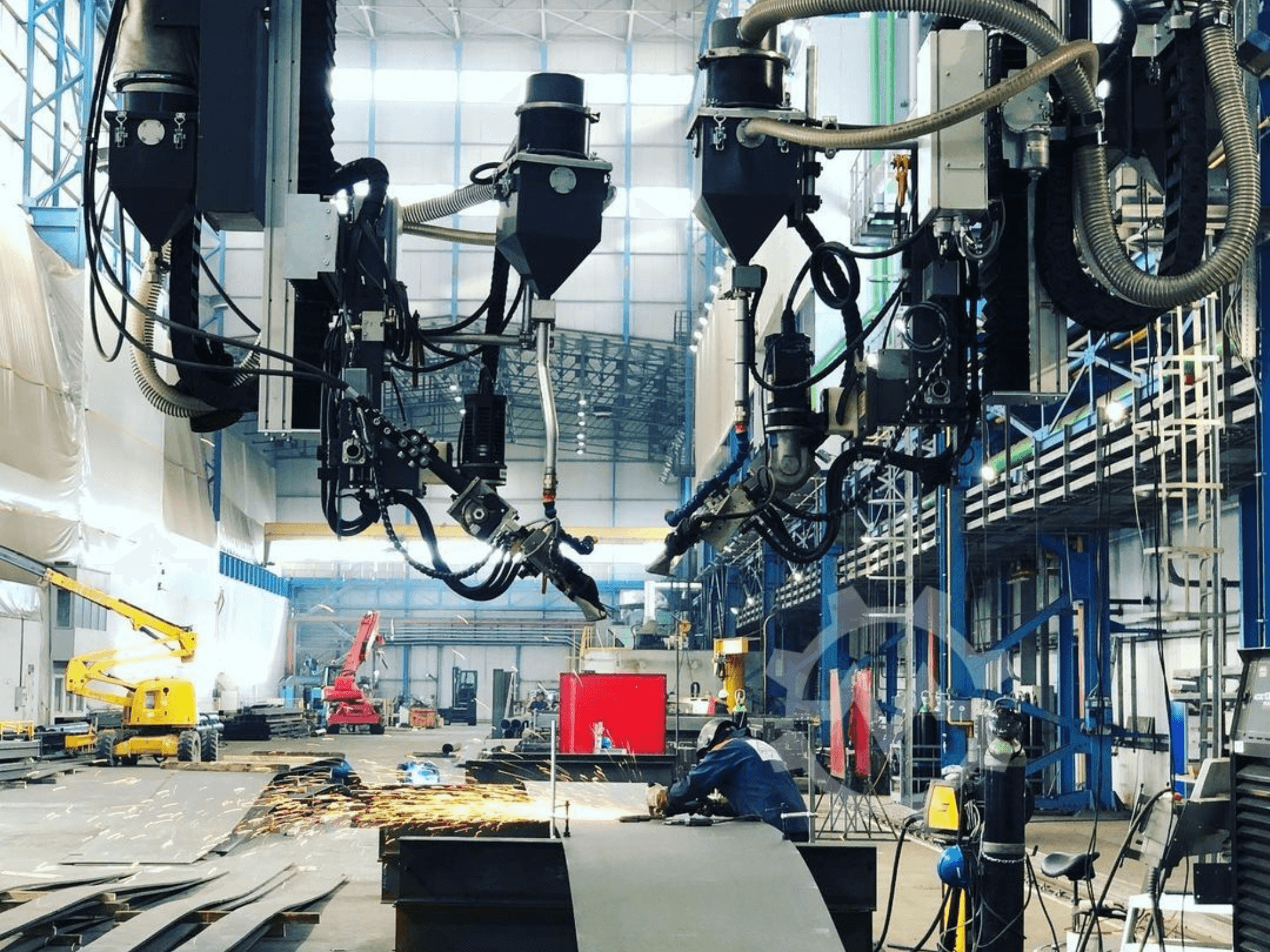 Macchina da taglio robotizzata in un ambiente industriale, con scintille che volano, vista di lato; dispone di più attacchi e tubi flessibili.
