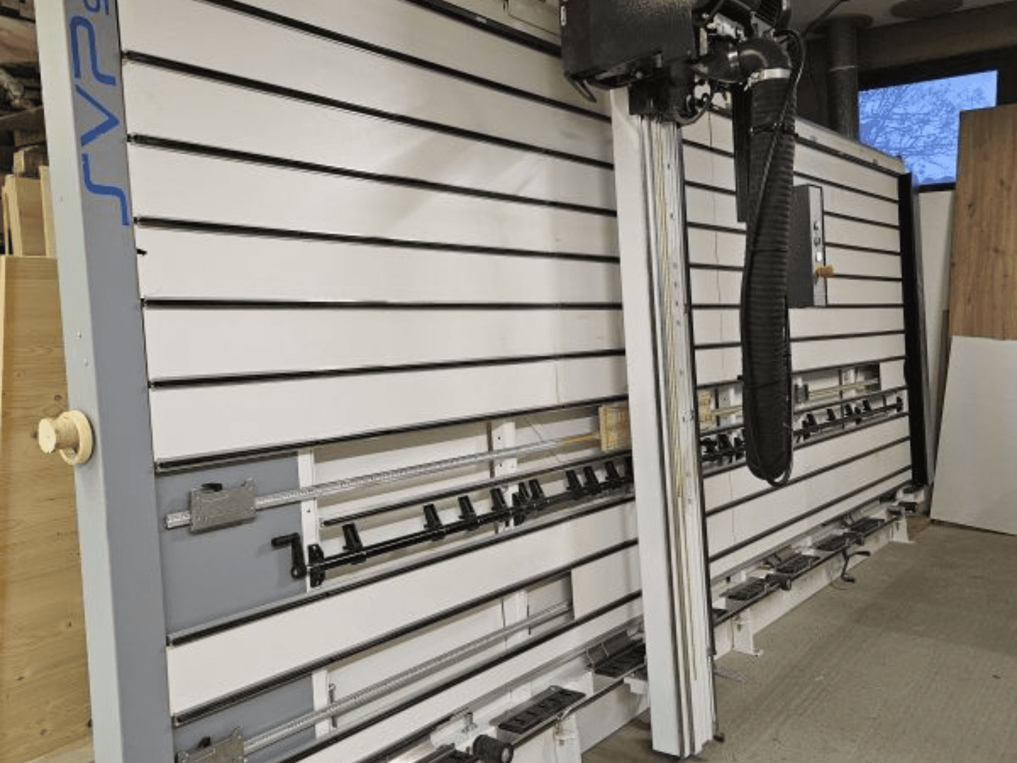 Sezionatrice scorrevole SVP in un'officina, vista frontale, con binari regolabili e sistema di aspirazione a soffitto.