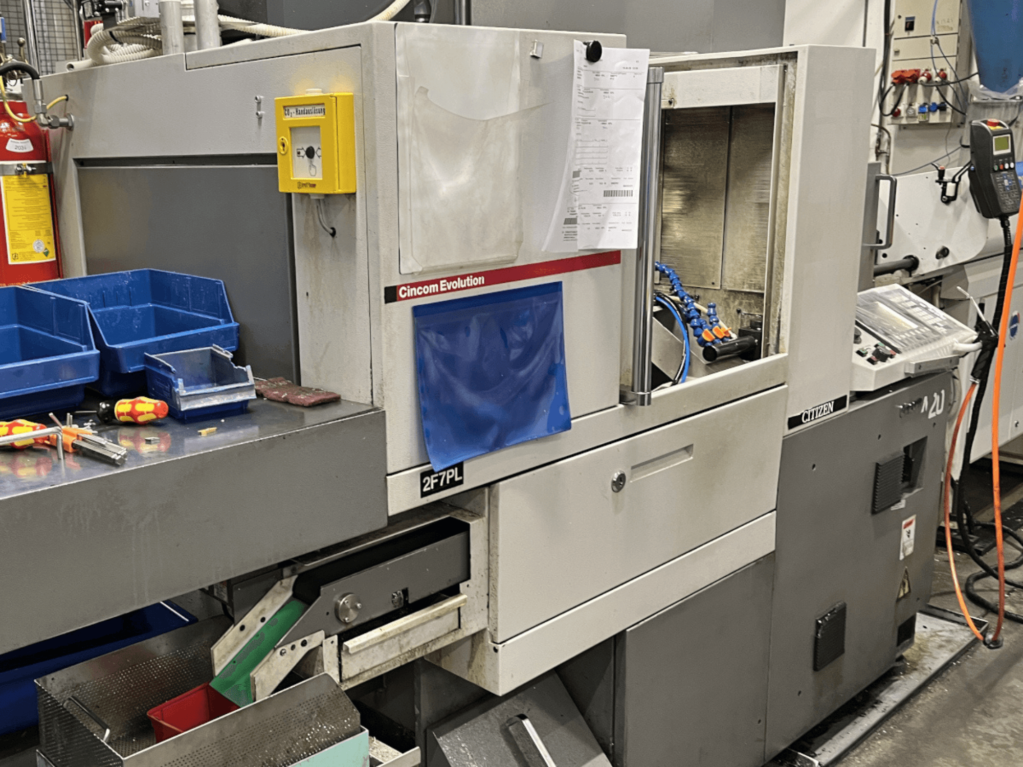 Centro di lavoro Cincom Evolution 2F7PL, vista frontale; presenta comandi, contenitori per utensili e un pannello operativo dettagliato.