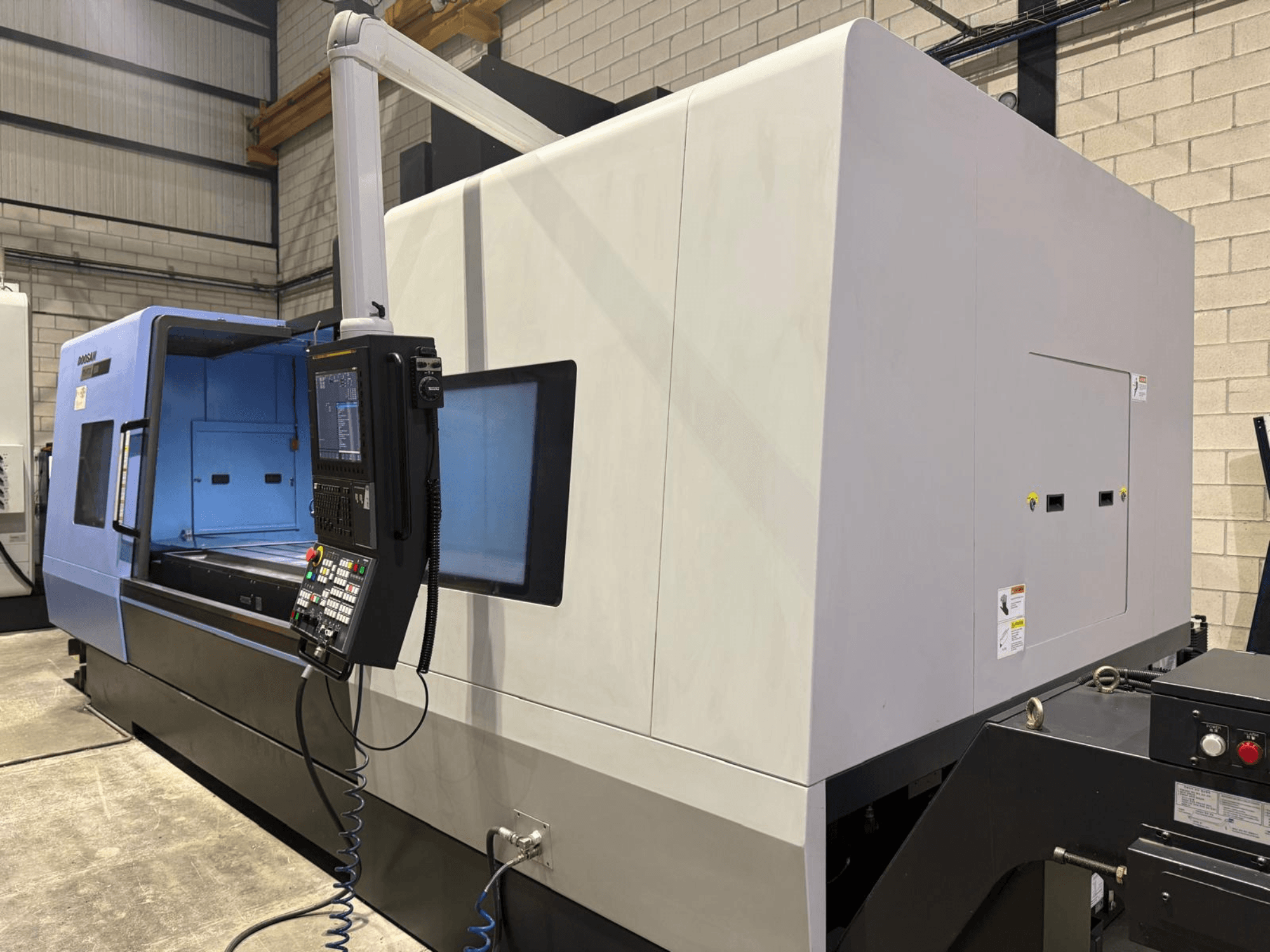 Tornio industriale CNC, esterno blu e grigio, vista frontale; dispone di un pannello di controllo con pulsanti e display per operazioni precise.