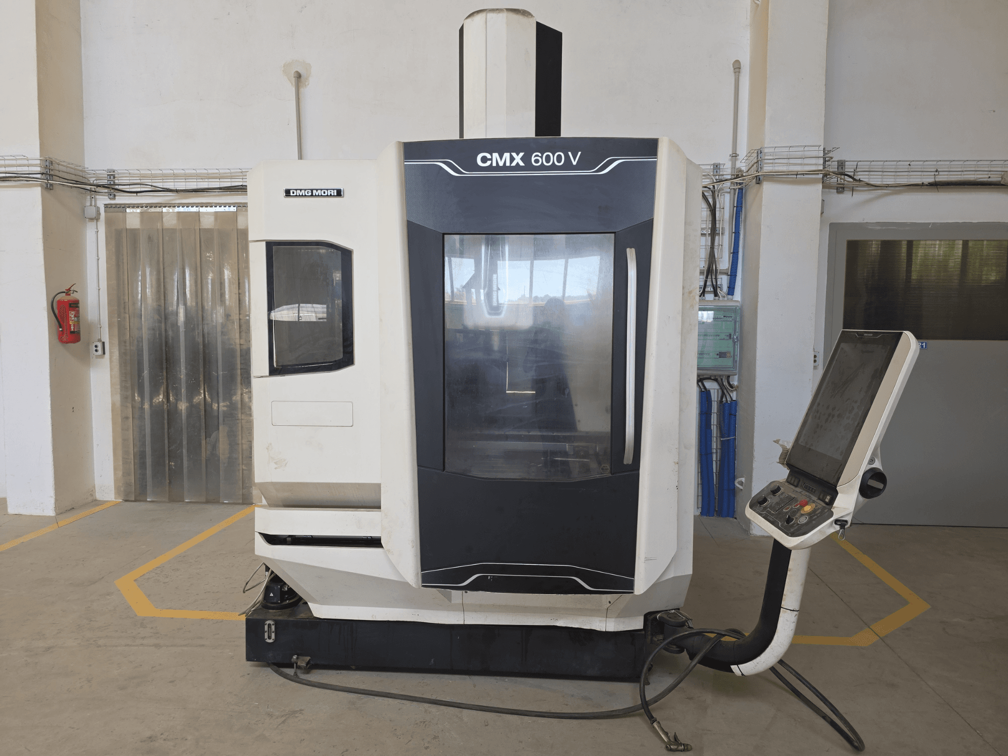 Centro di lavoro verticale DMG MORI CMX 600 V, vista frontale, con pannello di controllo e ampia finestra trasparente.