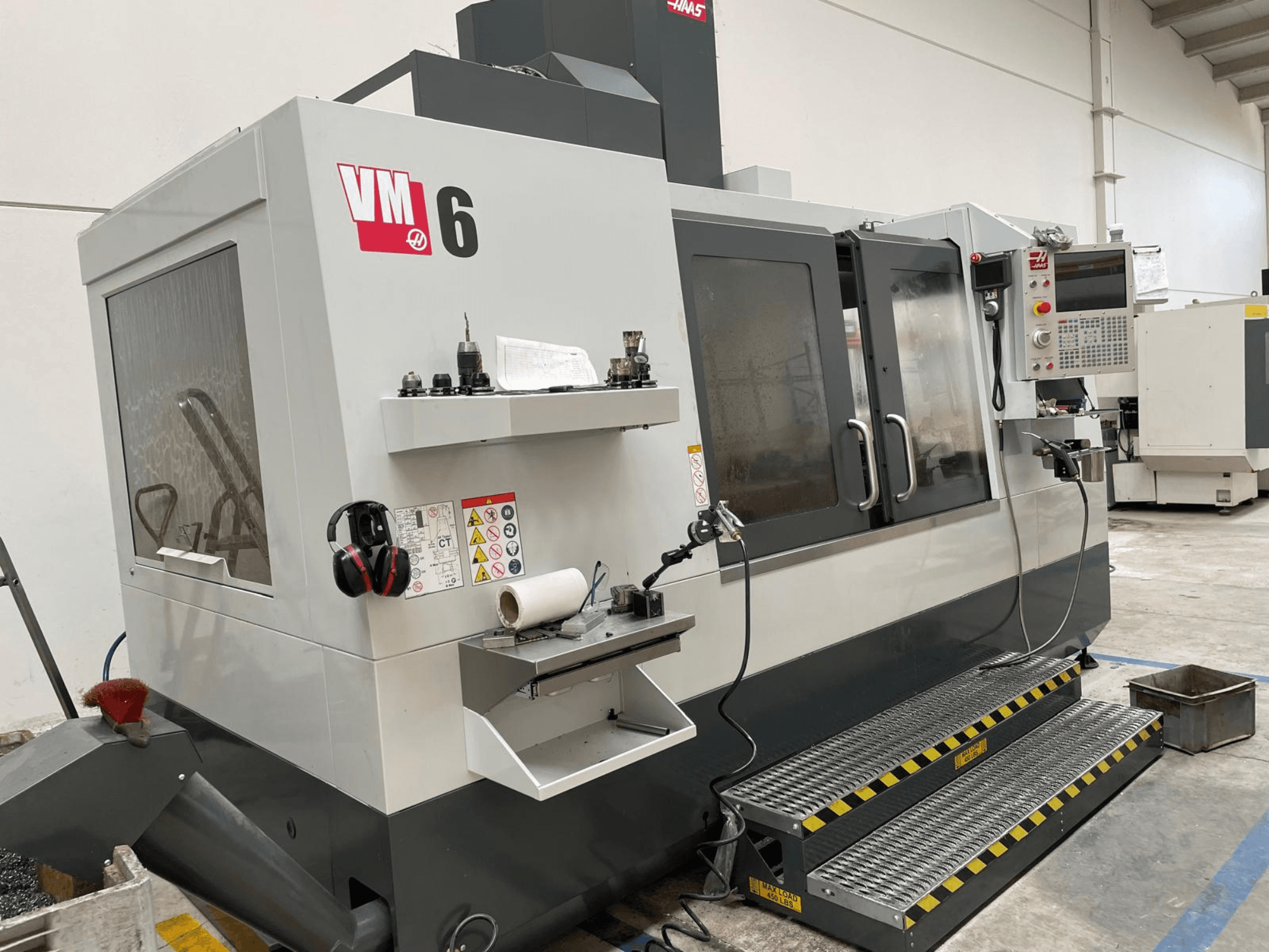 Centro di lavoro verticale Haas VM-6, vista frontale che mostra il pannello di controllo, i portautensili e le funzioni di sicurezza.