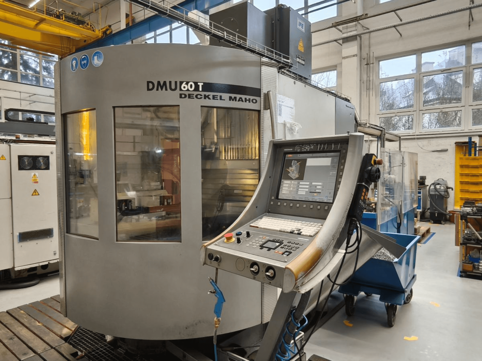 Vista verticale del centro di lavoro DECKEL MAHO DMU 60T con pannello di controllo, che visualizza utensili di precisione all'interno di un'officina.