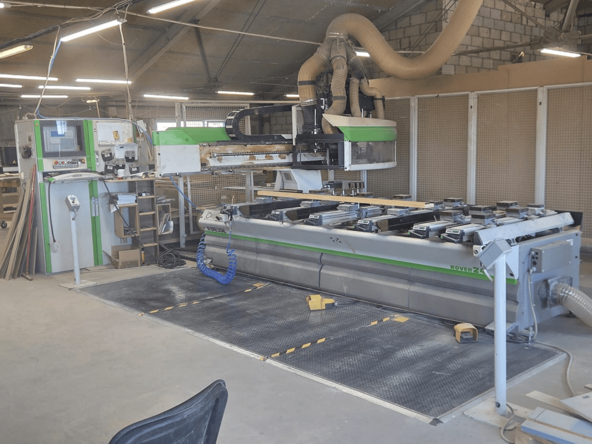 Centro di lavorazione CNC BIESSE Rover 24S in un'officina, con pannello di controllo e ampia superficie di lavoro con pezzi di legno.