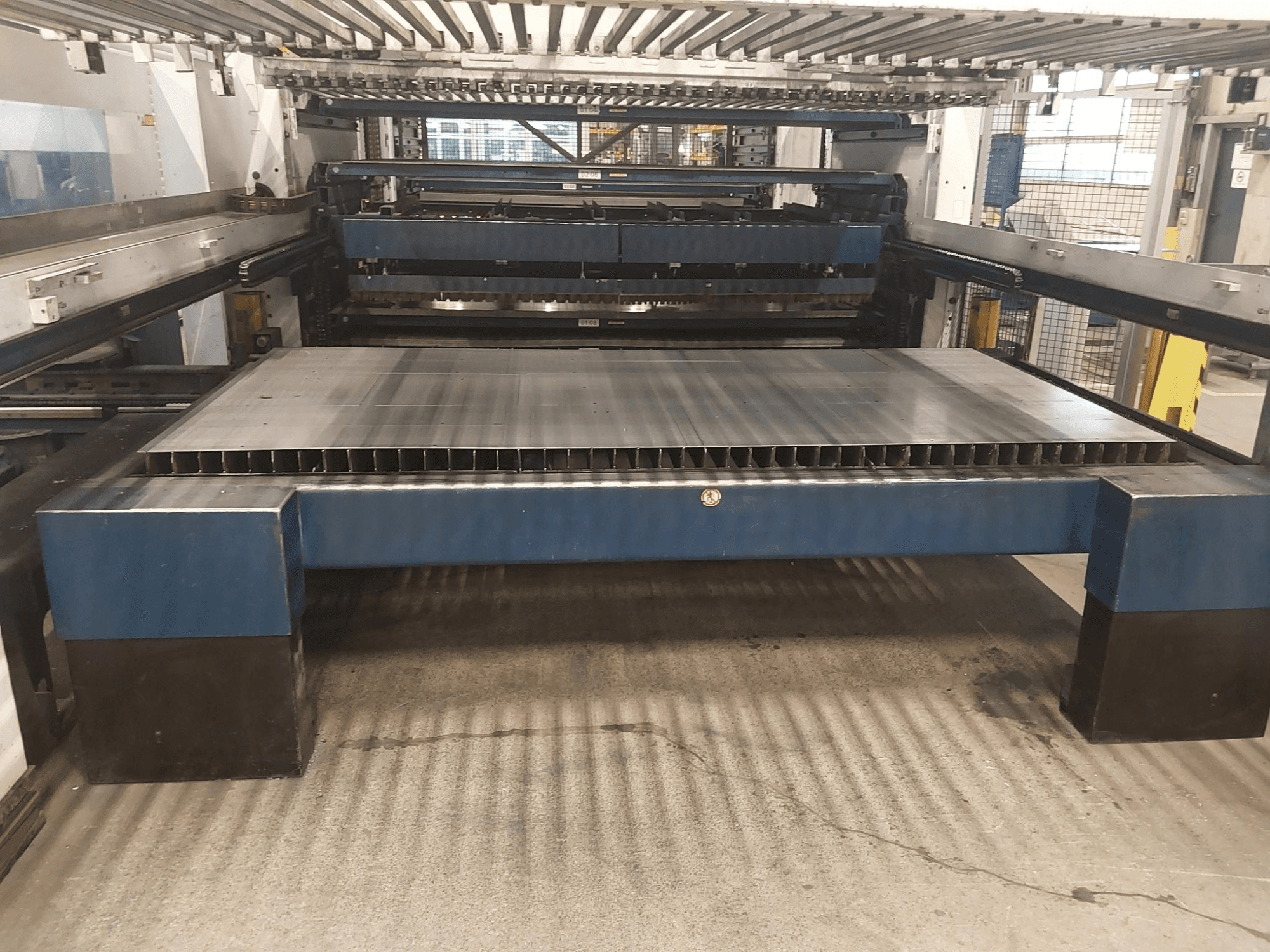 Vista frontale della macchina di taglio laser CO2 TRUMPF TruLaser 3030 L20 con un ampio banco di taglio e struttura di supporto.