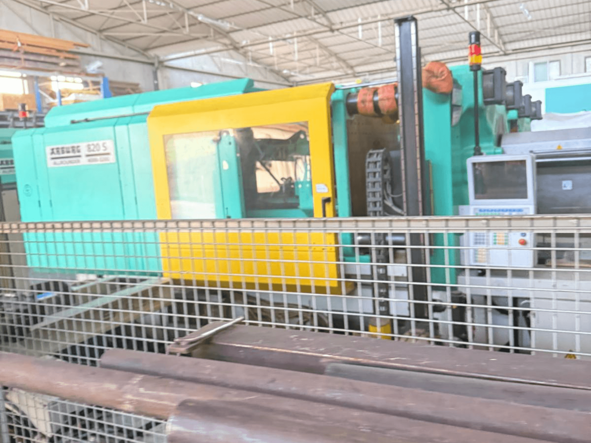 Pressa a iniezione idraulica Arburg SELECTA 820 S 4000-3200, vista laterale, che mostra il pannello di controllo e il vivace design giallo e verde acqua.