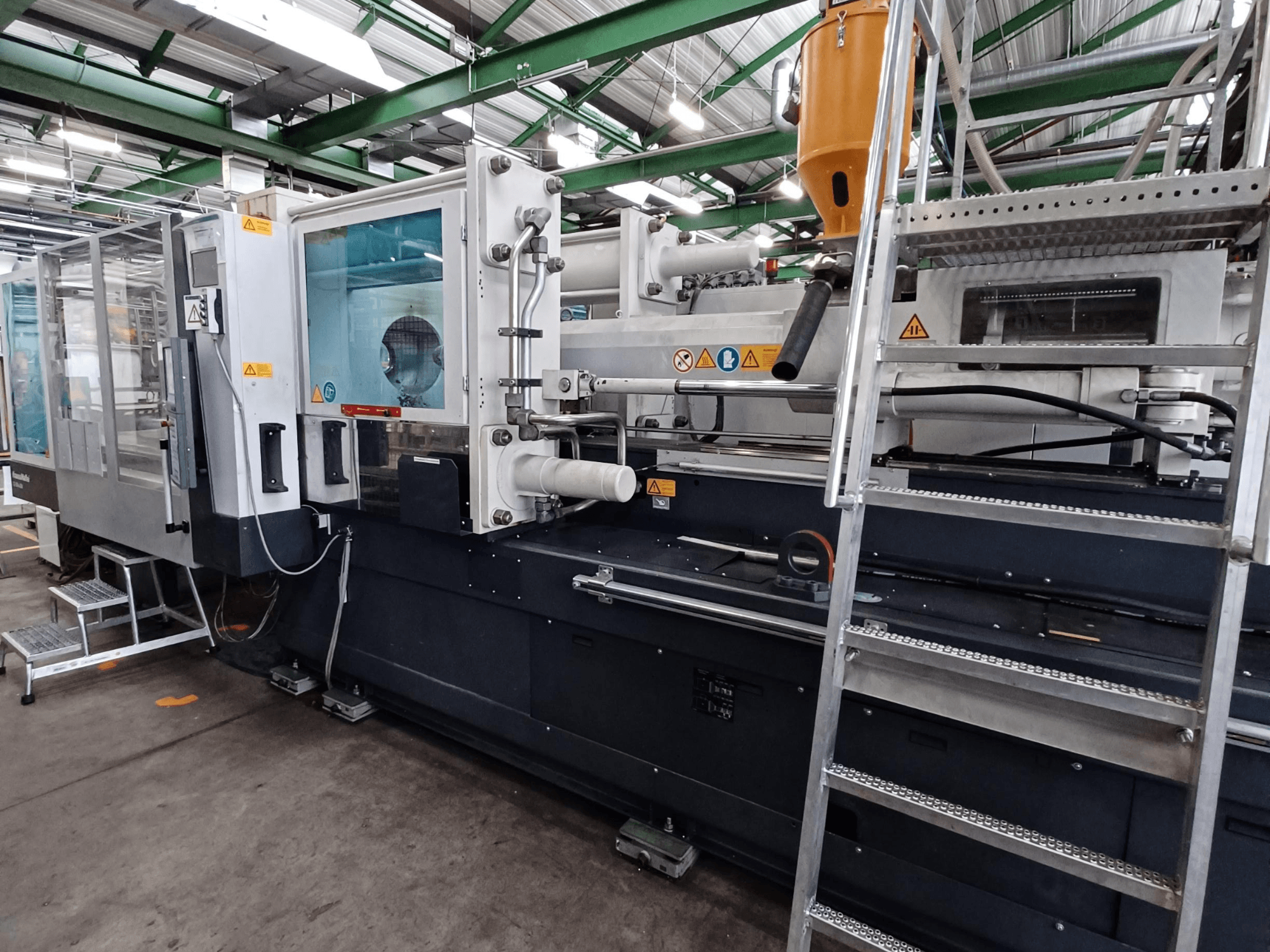 Macchina industriale per lo stampaggio a iniezione con una chiara vista frontale, che mostra le marcature del marchio, il pannello di controllo e la tramoggia del materiale.