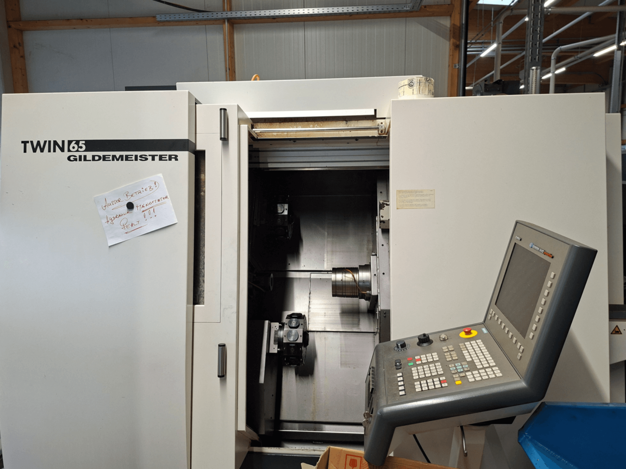 Tornio Gildemeister TWIN 65 CNC, vista frontale che mostra il pannello di controllo e la camera parzialmente aperta con i macchinari visibili.