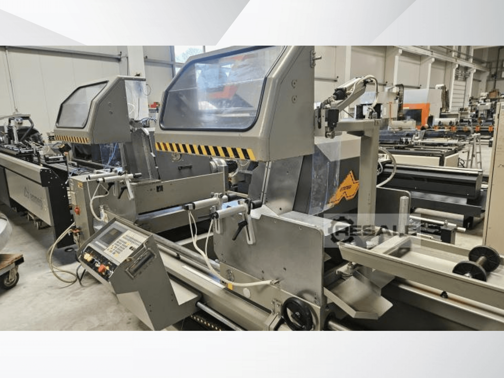 Macchine a doppia sega in un ambiente di fabbrica; vista frontale che mostra il pannello di controllo, le coperture in vetro e i componenti di taglio.