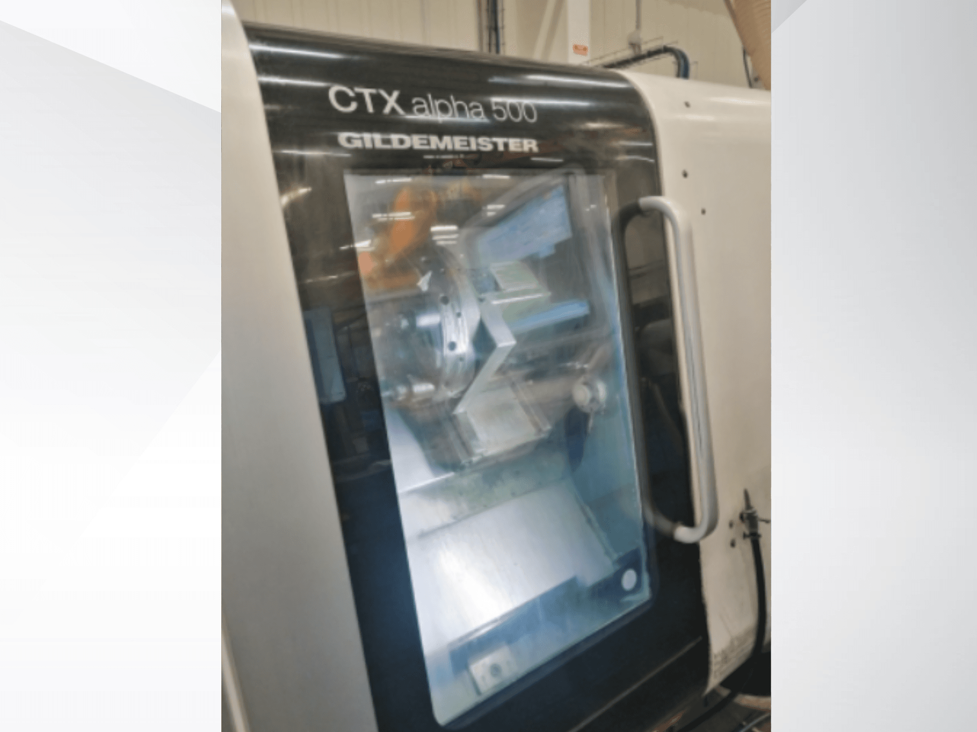 Macchina CNC CTX alpha 500 Gildemeister, vista frontale, che mostra il mandrino e l'area di lavorazione attraverso la porta di vetro.