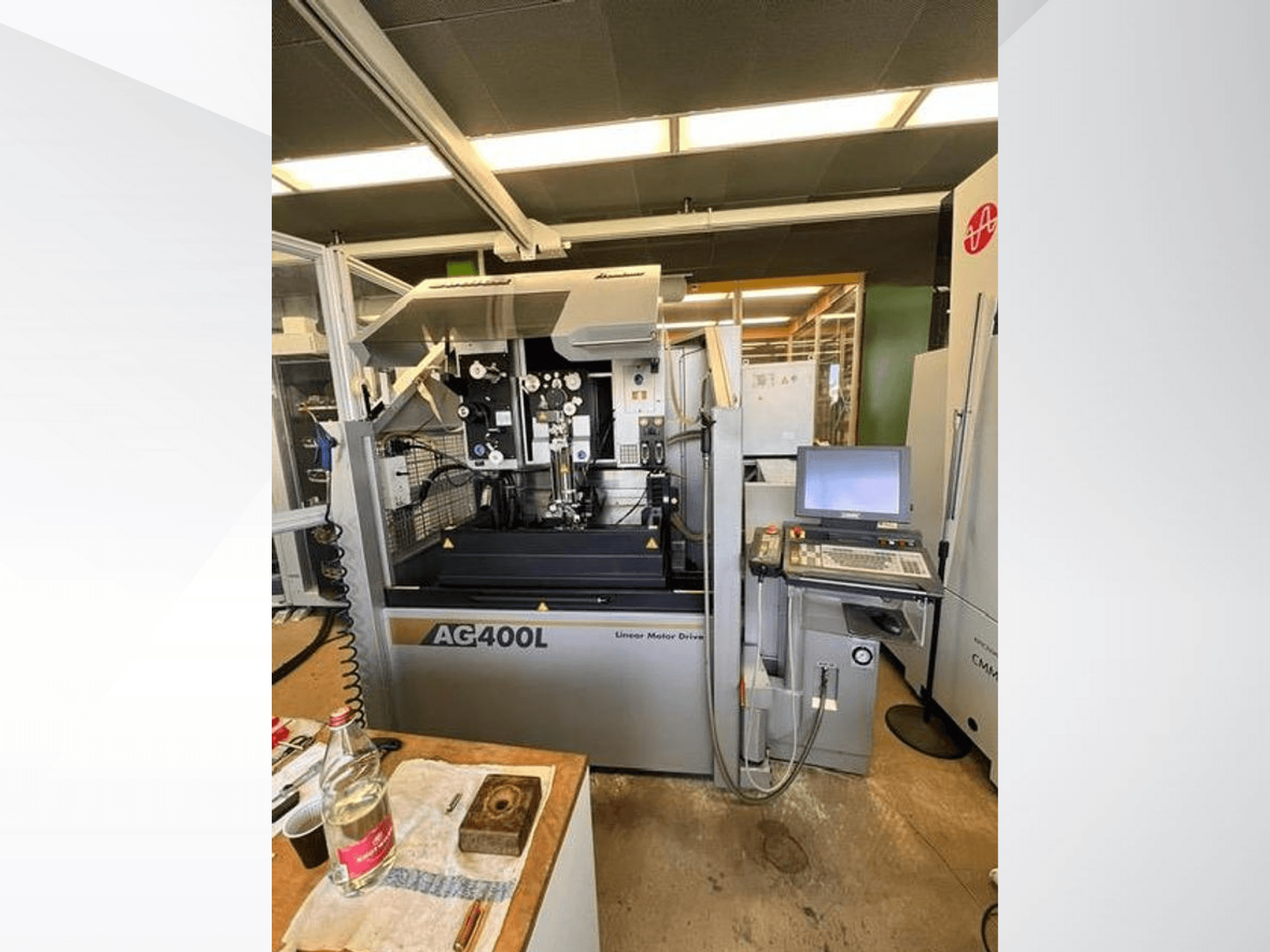 Macchina a motore lineare AG400L, vista frontale, con pannello di controllo e area di lavoro con caratteristiche di sicurezza visibili.