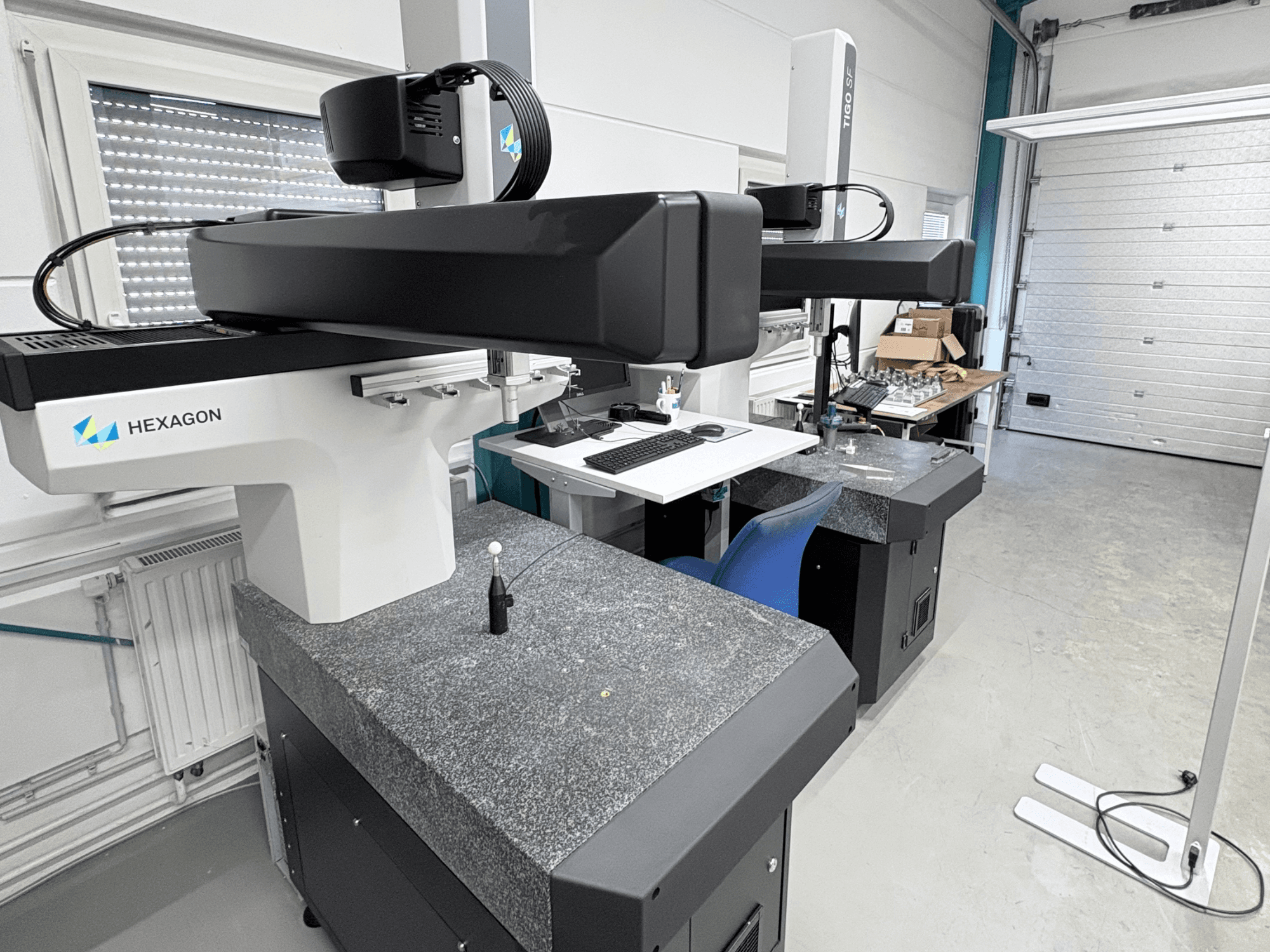 Macchina di misura a coordinate (CMM) Hexagon Tigo SF in officina, dotata di base in granito, sonda di misura e postazione di lavoro adiacente con utensili.