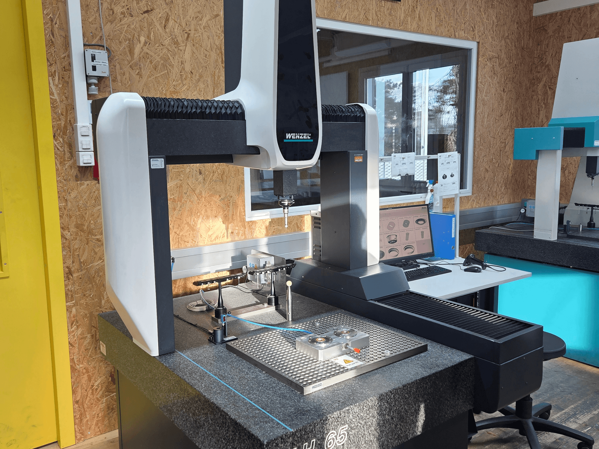 Macchina di misura a coordinate Wenzel LH 65 in un laboratorio, vista frontale, con strumenti di misura e monitor.