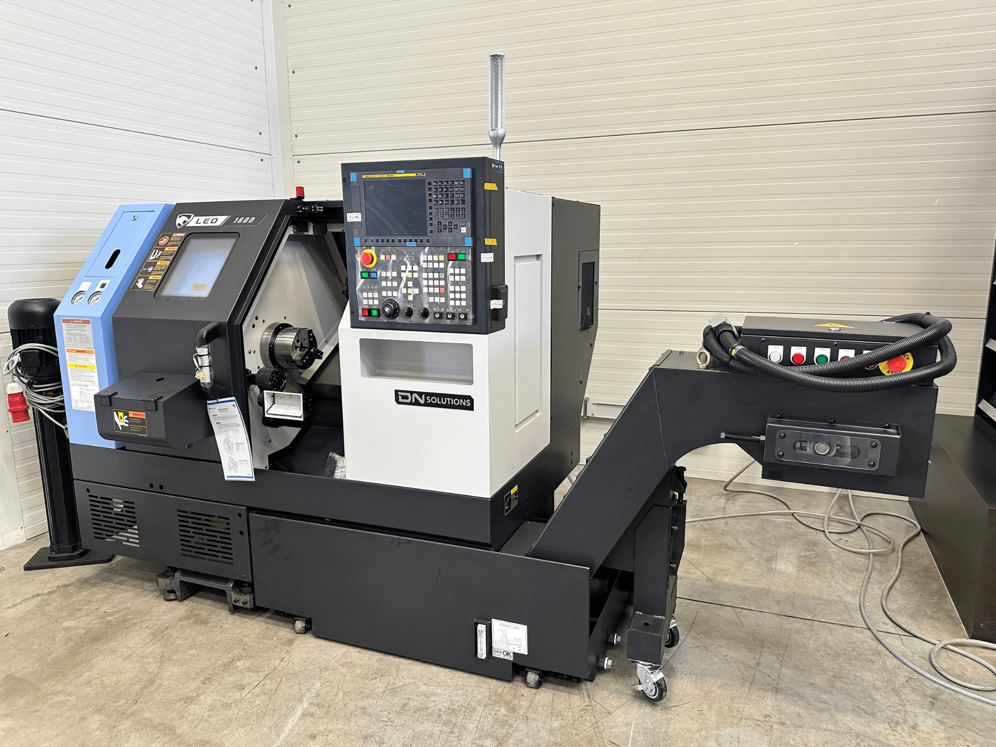 Vista frontale del centro di tornitura DN SOLUTIONS Leo 1600, con pannello di controllo digitale e portautensili, su base nera.