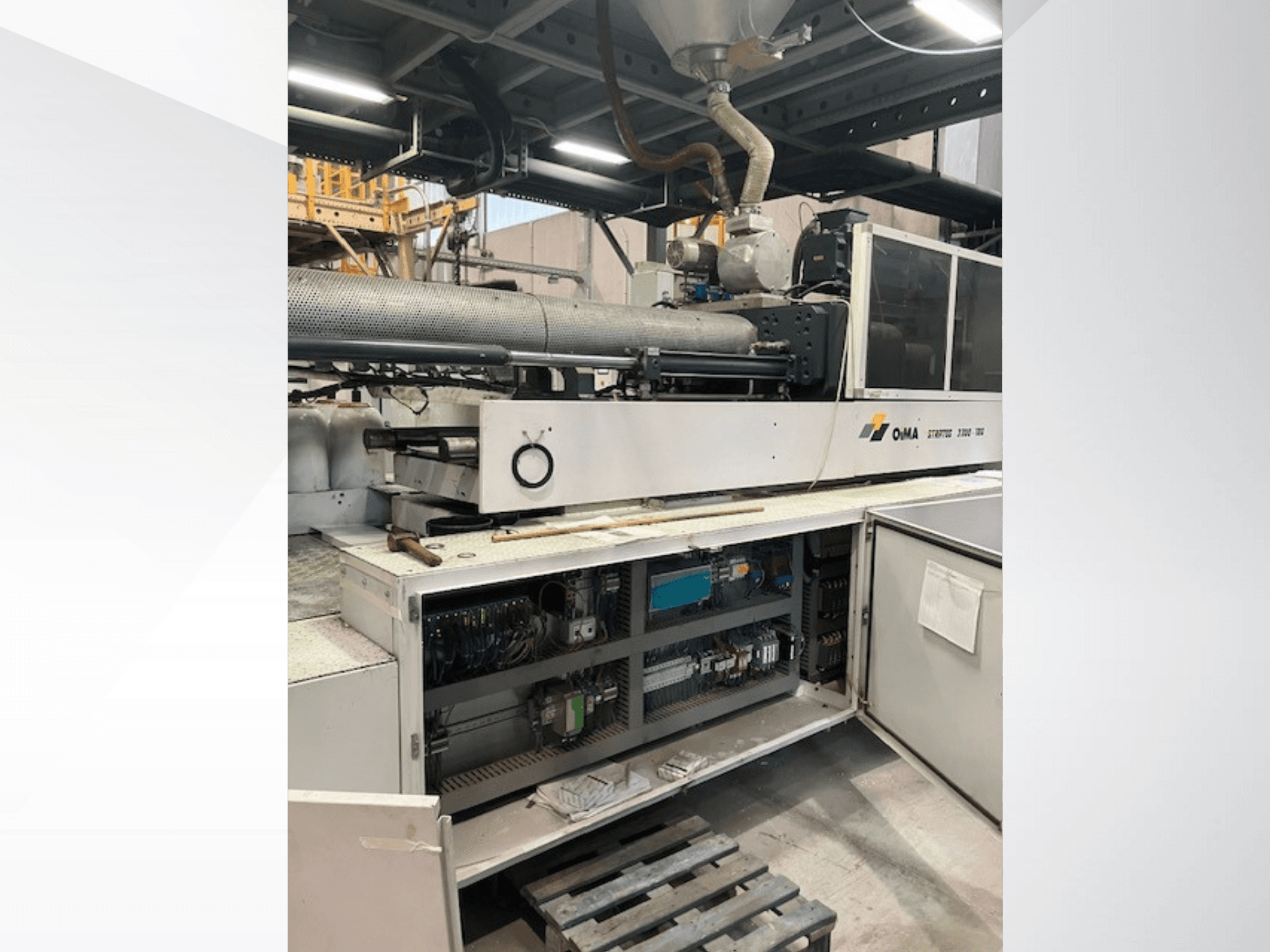 Vista frontale dell'estrusore OMA 3500, che mostra le parti operative, il pannello di controllo e i dettagli del cablaggio. Macchinario pesante in ambiente industriale.