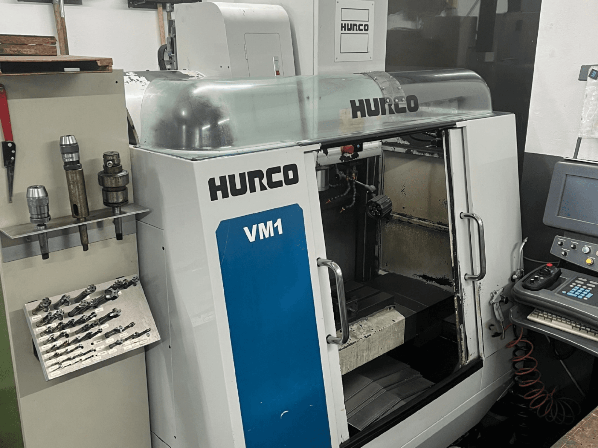 Centro di lavoro verticale Hurco VM1 vista frontale, con coperchio trasparente, pannello di controllo e utensili montati.