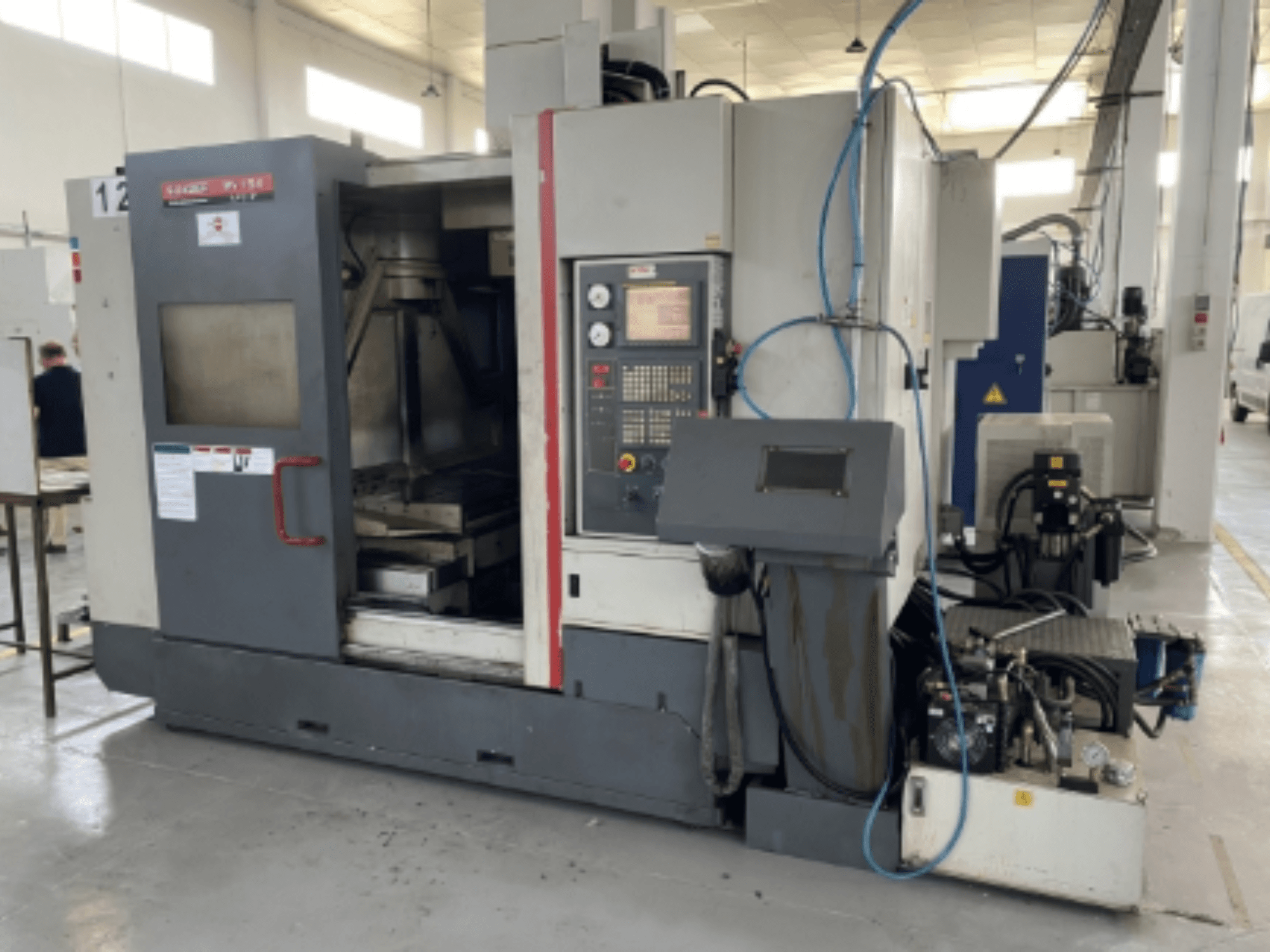 Centro di lavoro verticale Quaser MV154APC-912, vista frontale che mostra il pannello di controllo, lo sportello aperto e i componenti della macchina.