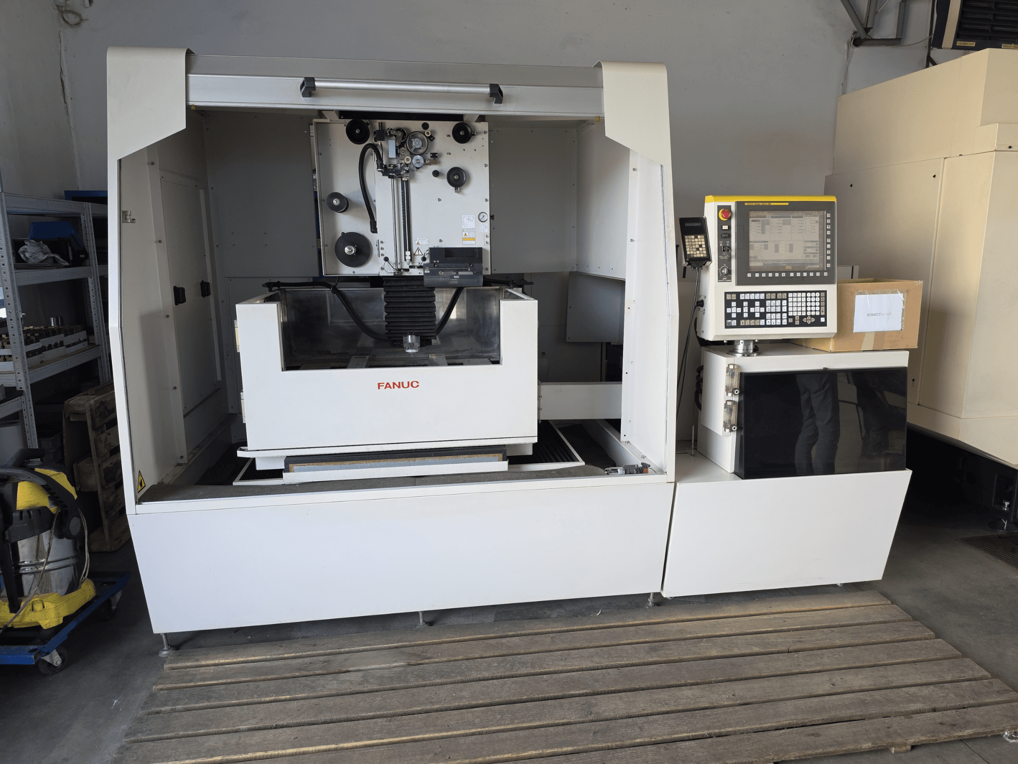 Macchina per elettroerosione a filo FANUC ROBOCUT alpha-1iD, vista frontale che mostra il pannello di controllo, l'area di lavoro e il design compatto in un ambiente di officina.