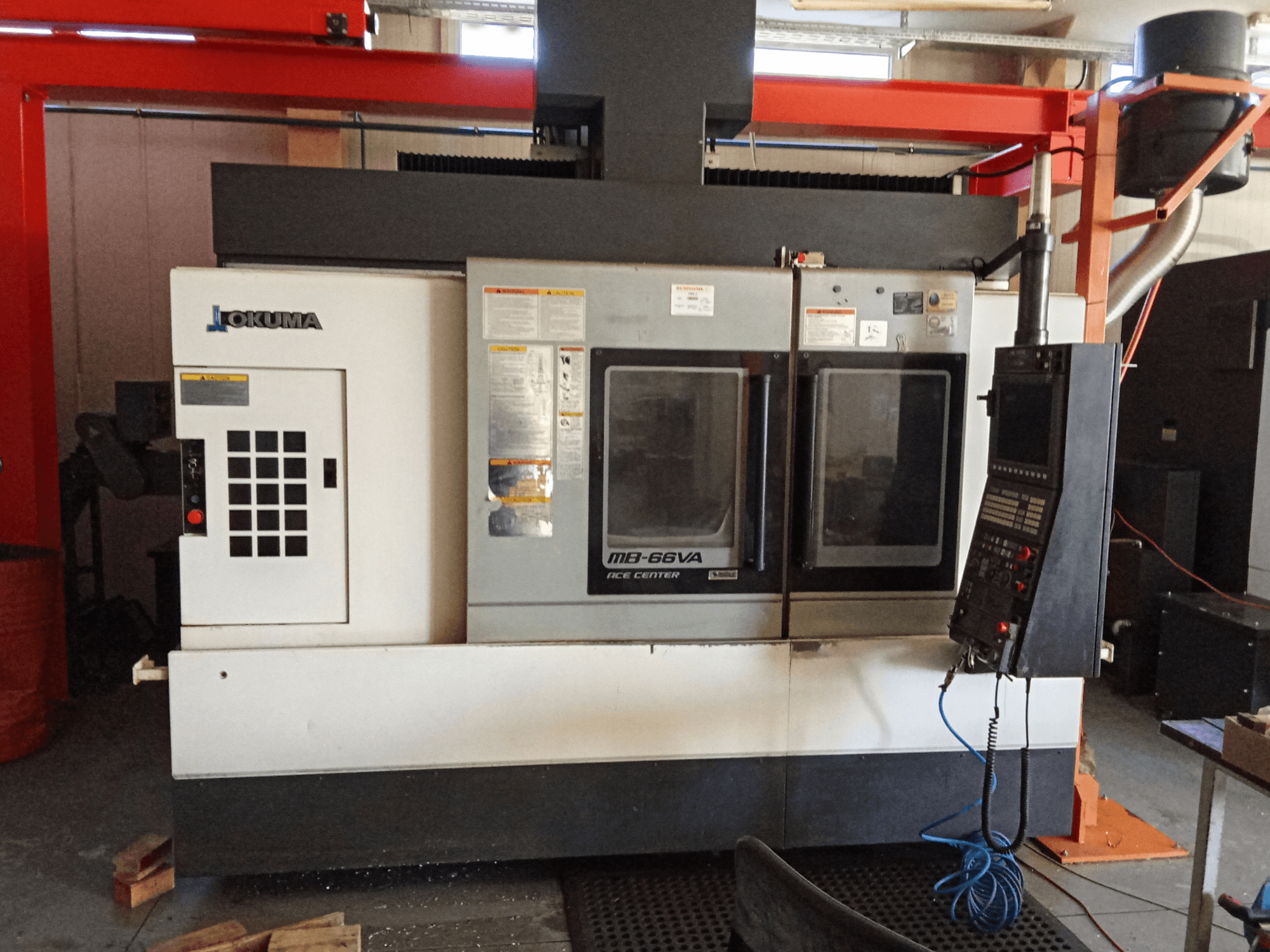 Centro di lavoro verticale Okuma MB-66VA, vista frontale che mostra il pannello di controllo e le doppie finestre di visualizzazione per l'accesso agli utensili.