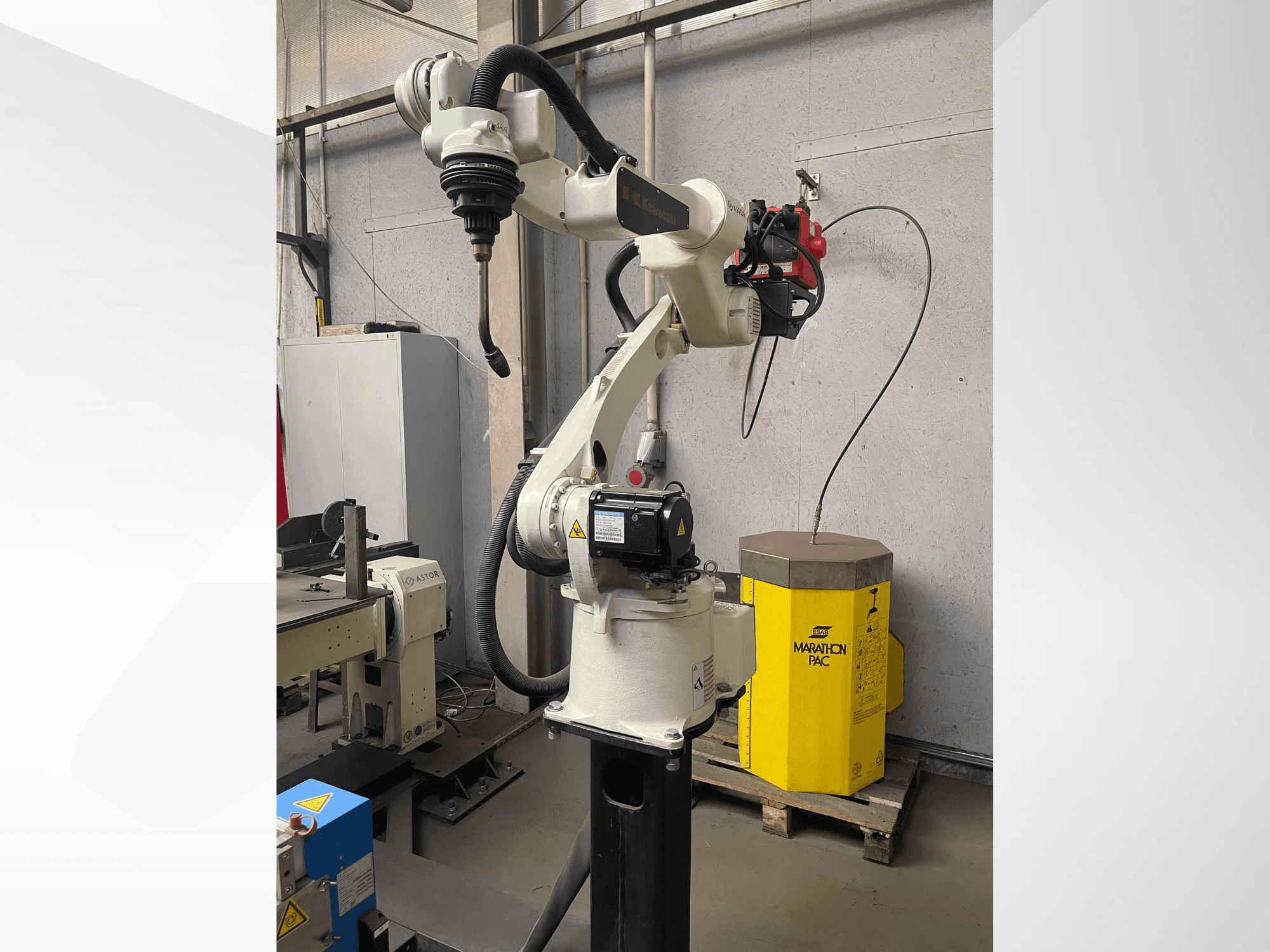 Braccio robotico Kawasaki da una vista laterale, con un portautensili montato e un'unità di potenza gialla sullo sfondo.