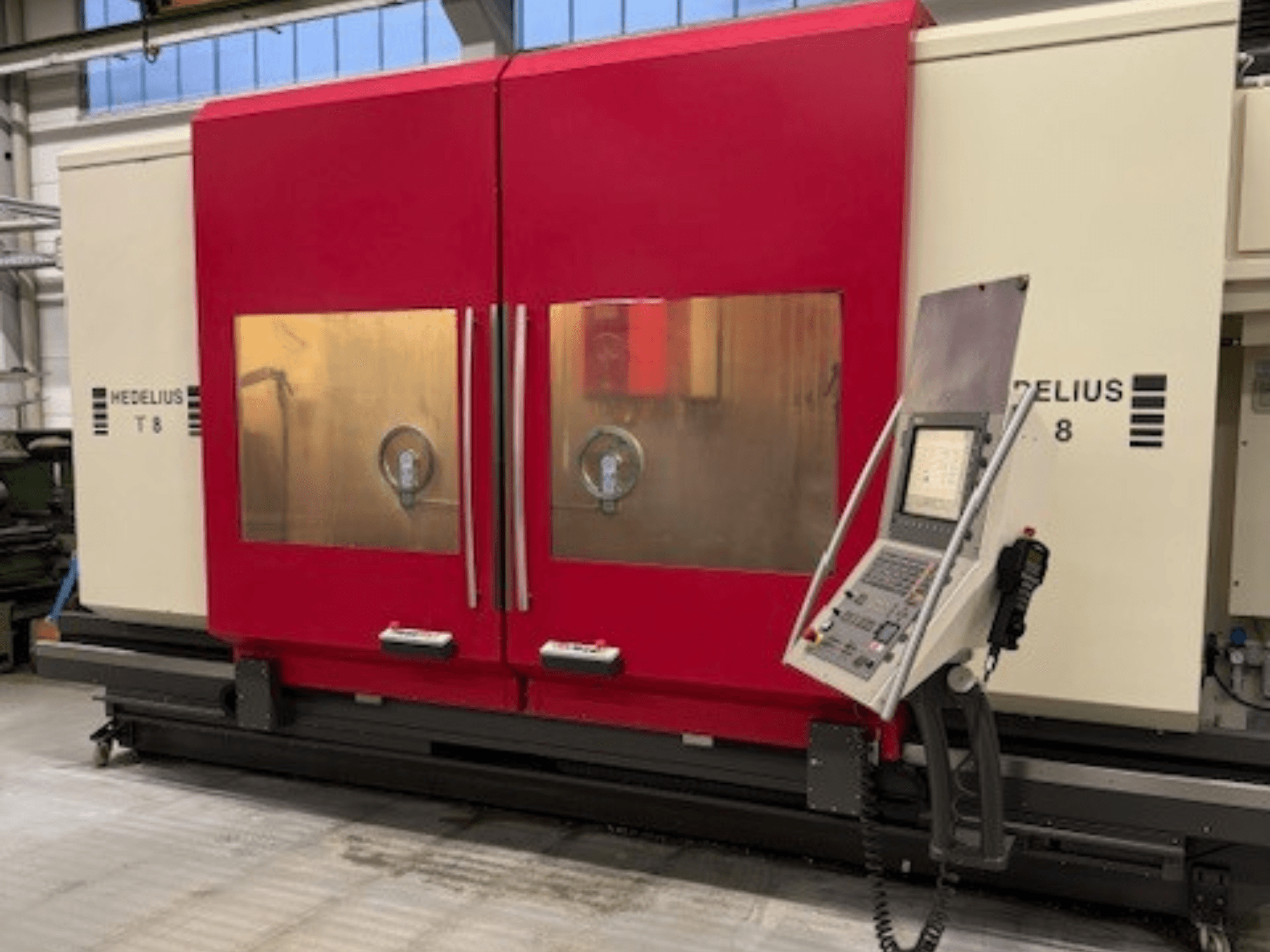 Macchina CNC HEDELIUS T8 in vista frontale, con porte rosse, pannello di controllo e visibilità dei componenti interni.