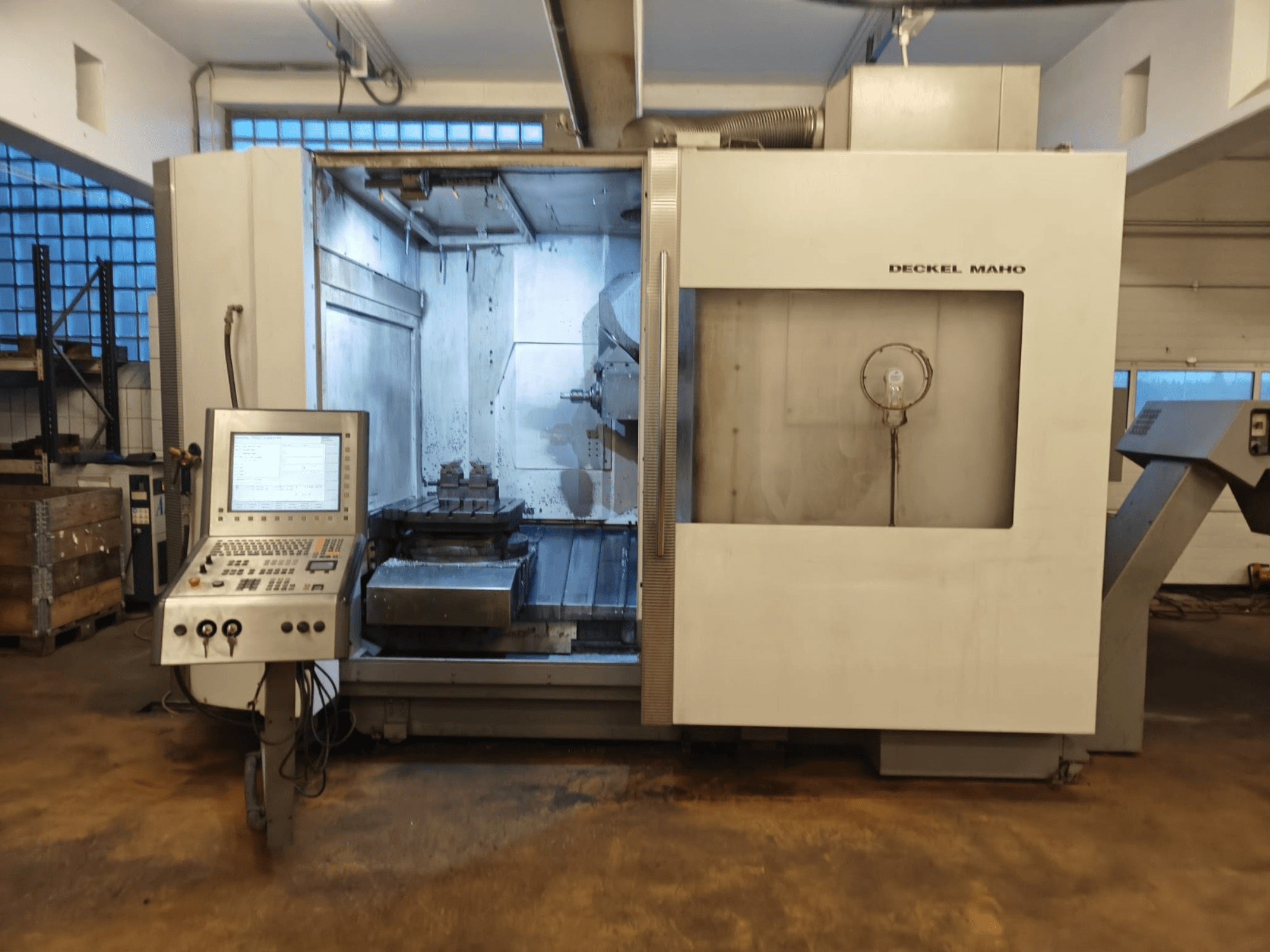 Centro di lavoro universale DECKEL MAHO DMC 60U, vista frontale, con pannello di controllo e area di lavorazione con impostazione del pezzo.