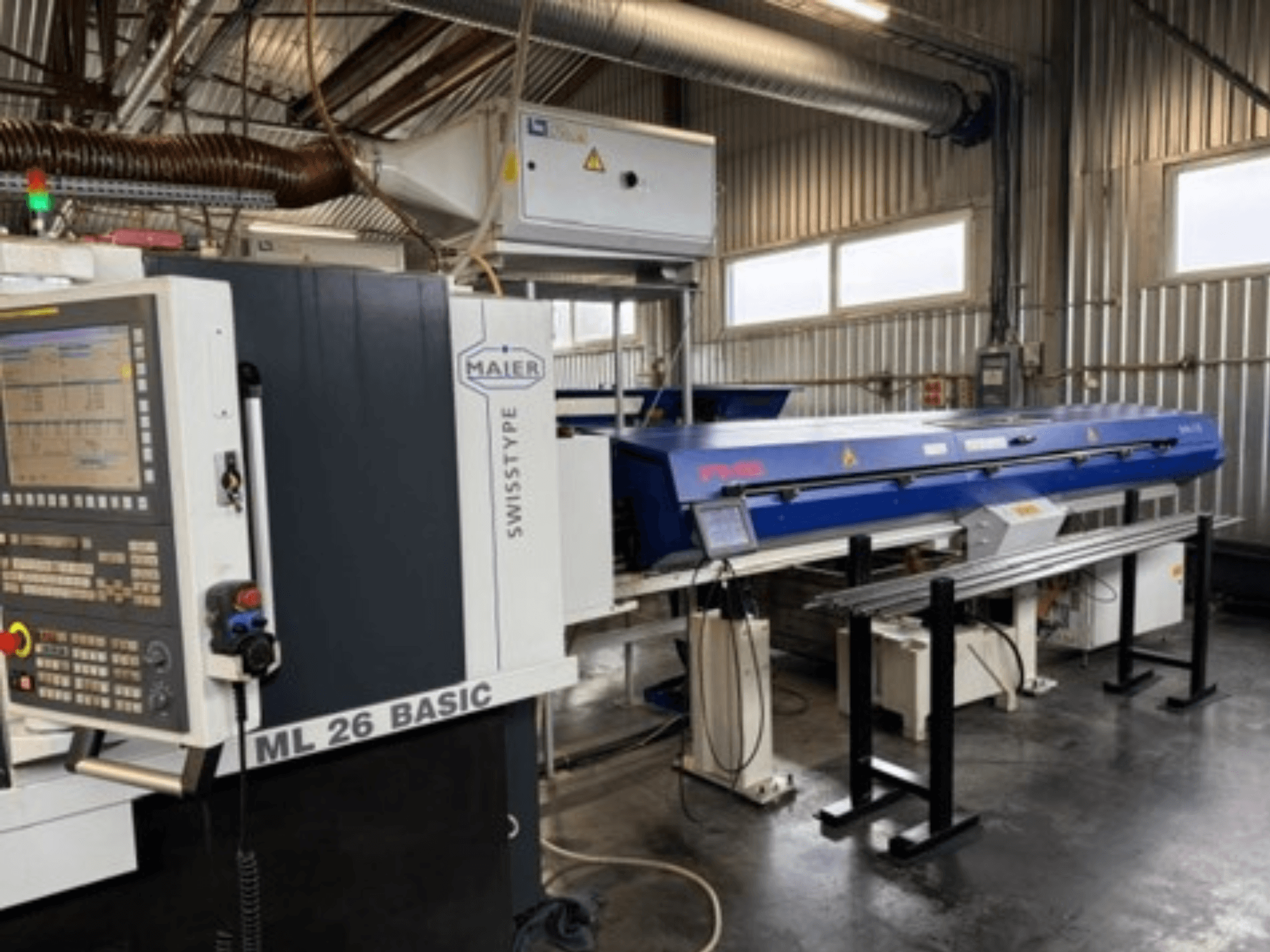 Testo alternativo: Vista frontale del tornio svizzero Maier ML26 C5Y con pannello di controllo e dispositivo blu collegato, in un ambiente industriale.