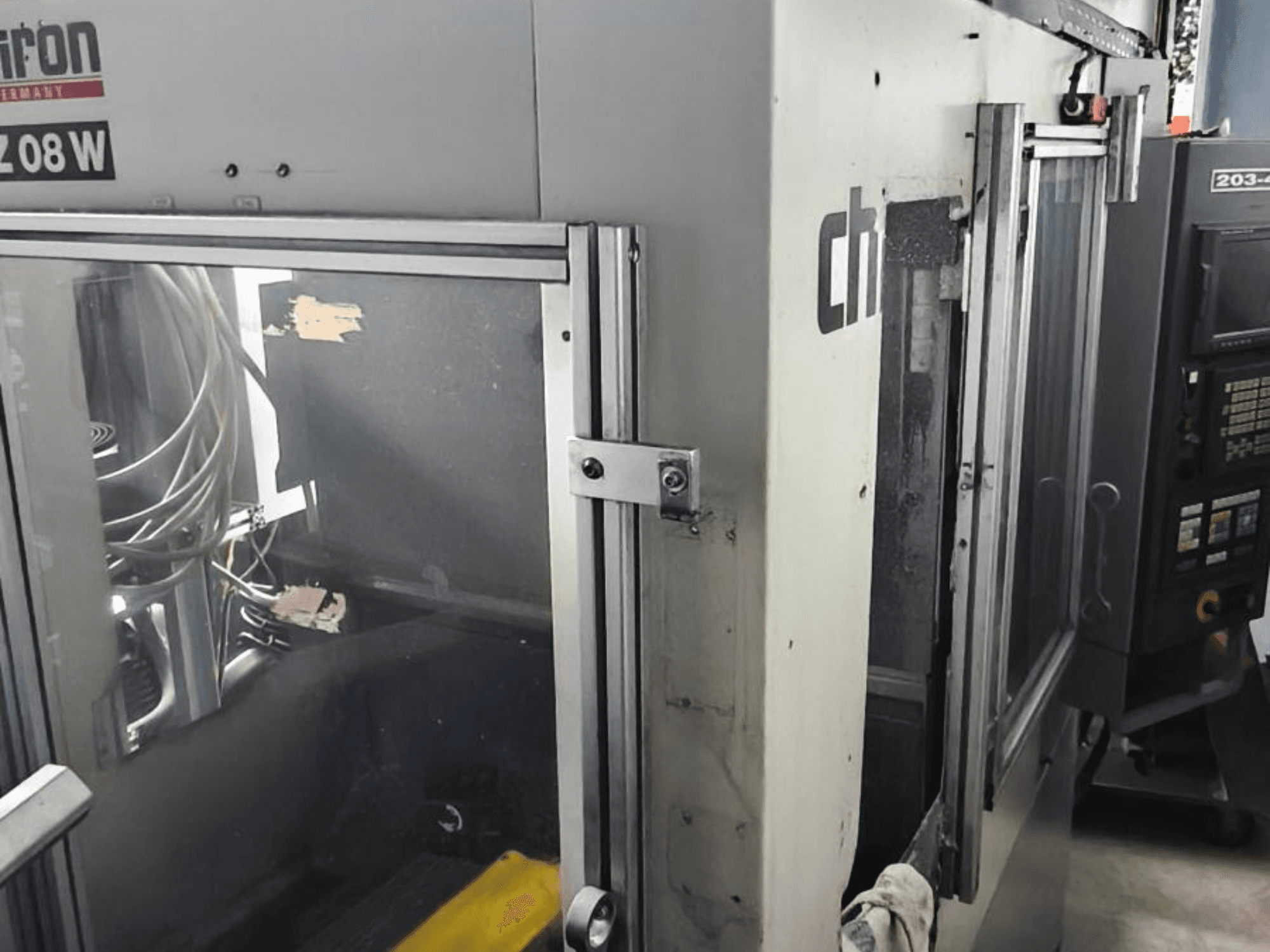 Centro di lavoro verticale CHIRON FZ 08 W, vista frontale con pannello di controllo e porte parzialmente aperte, con componenti interni visibili.